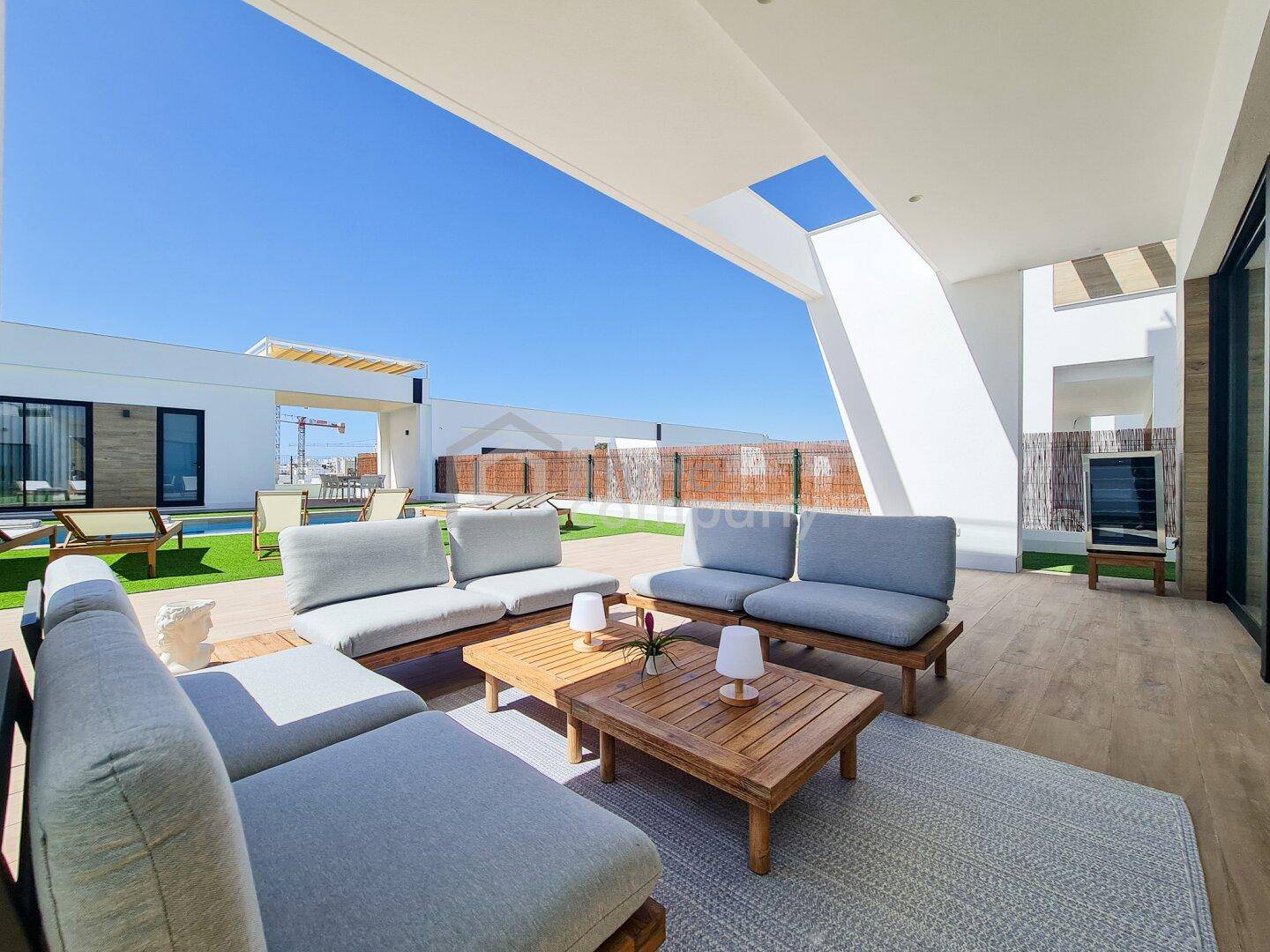 Geräumige Terrasse mit moderner Lounge-Möblierung und Blick auf den Poolbereich und die Umgebung.