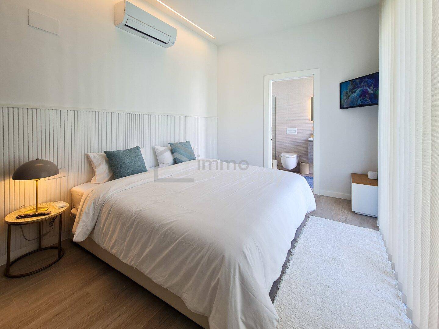 Komfortables Schlafzimmer mit Klimaanlage und direktem Zugang zu einem modernen Badezimmer.