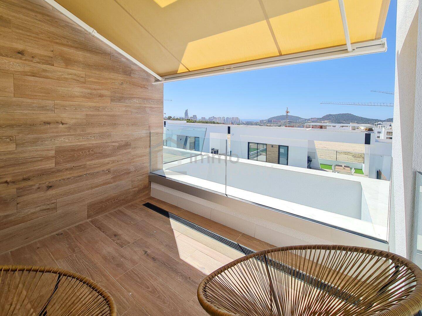 Heller Balkon mit Holzoptikfliesen, Glasgeländer und weitem Blick auf Stadt und Berge.
