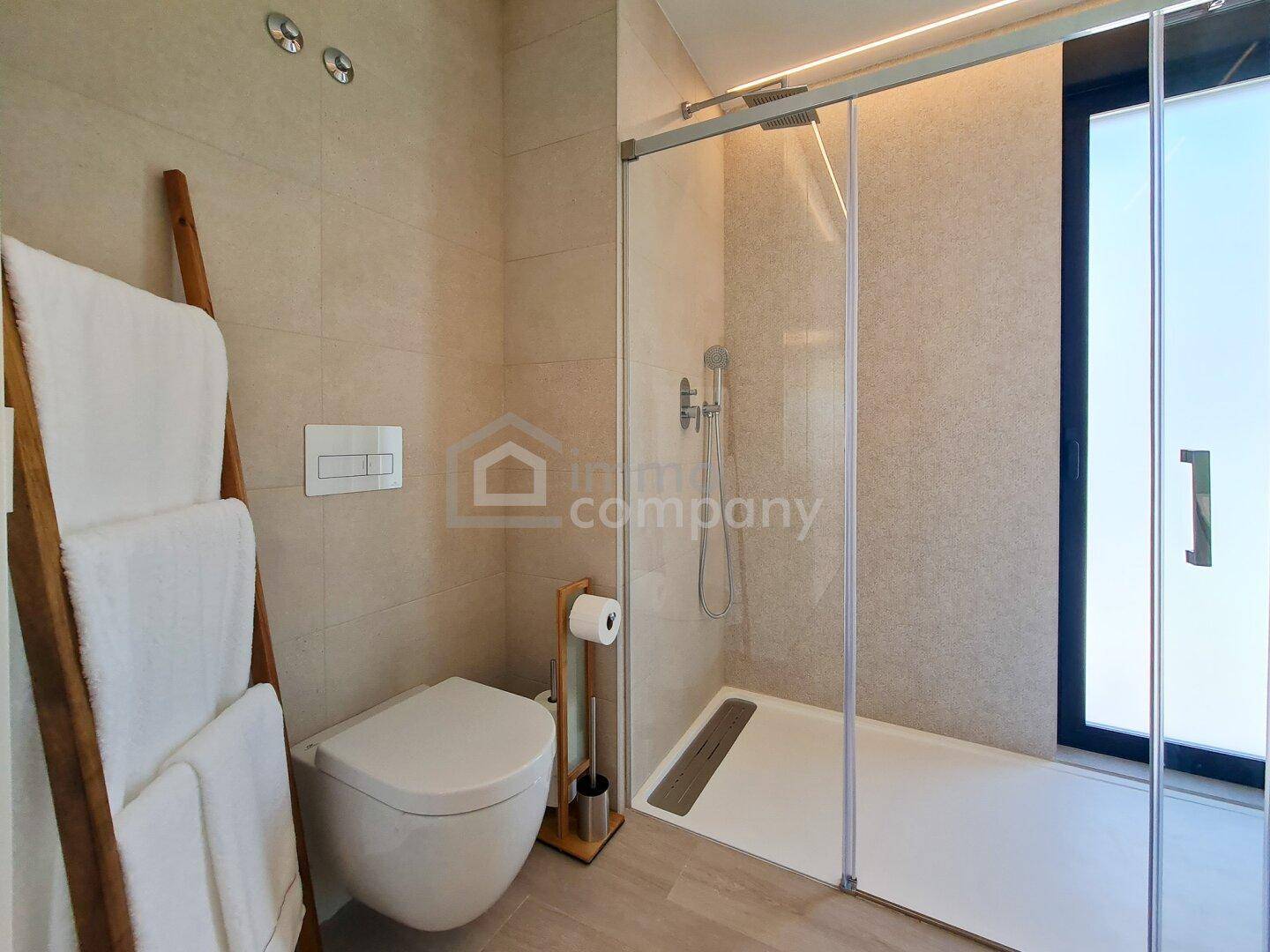 Elegantes Badezimmer mit wandhängendem WC und geräumiger, ebenerdiger Dusche.
