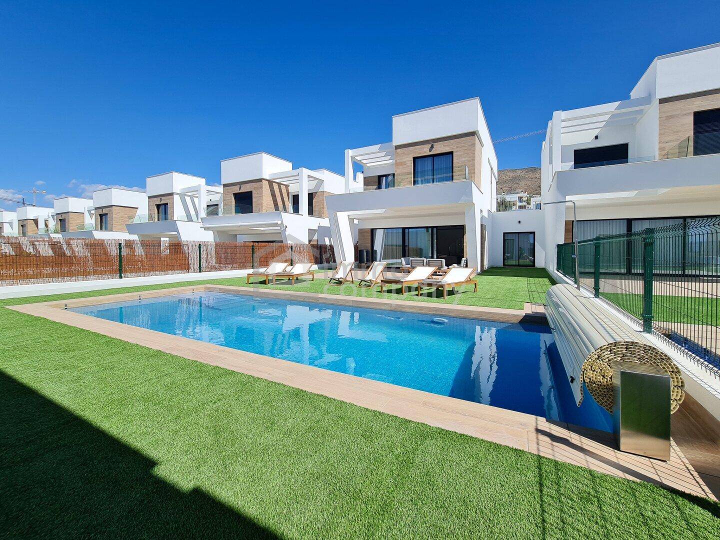 Weitläufiger Blick auf moderne Villen mit privatem Pool und gepflegtem Kunstrasenbereich.