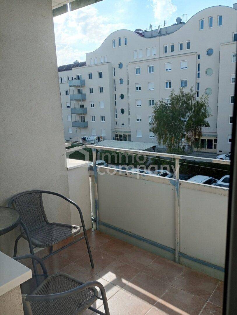 Kleiner Balkon mit Fliesenboden und Blick auf die umliegenden Gebäude.