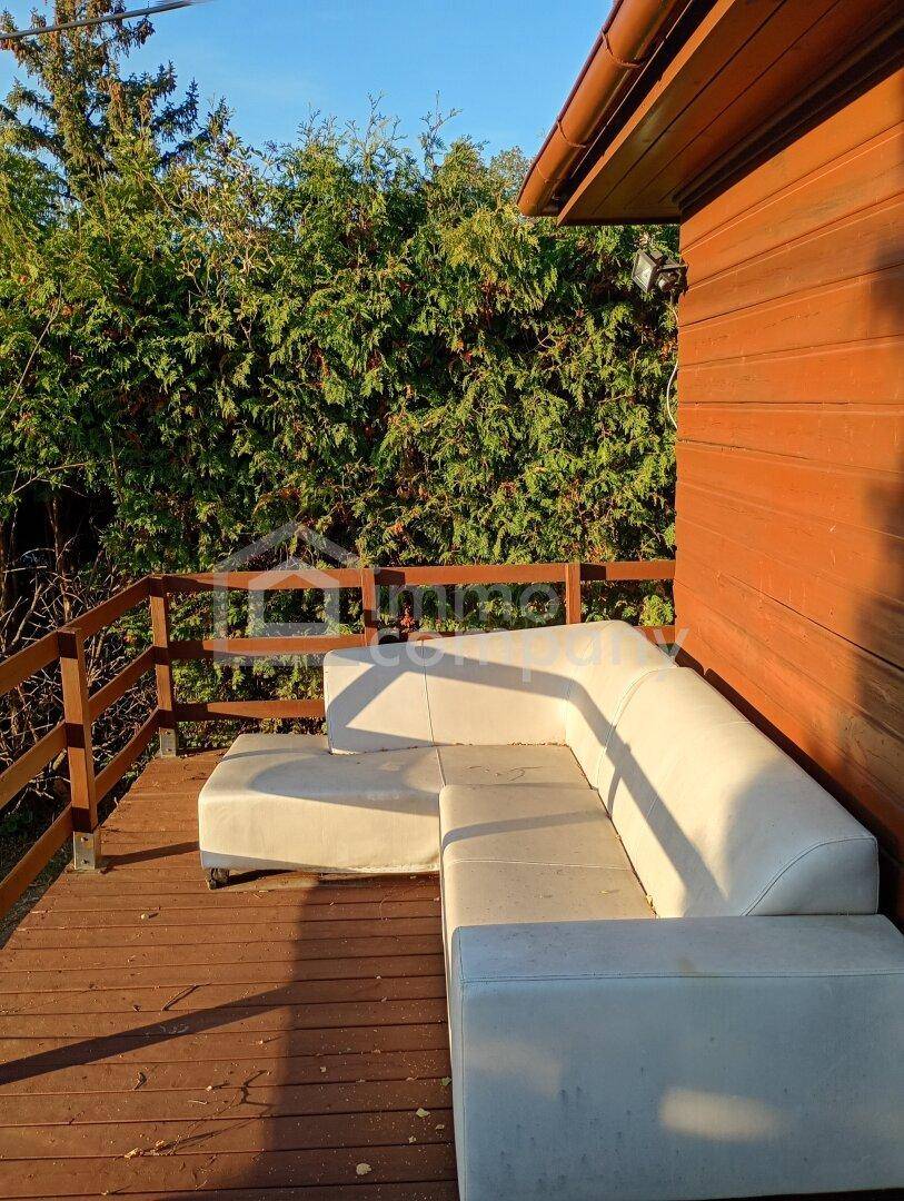 Gemütlicher Lounge-Bereich auf der Holzterrasse, umgeben von dichtem Grün und Holzwänden.
