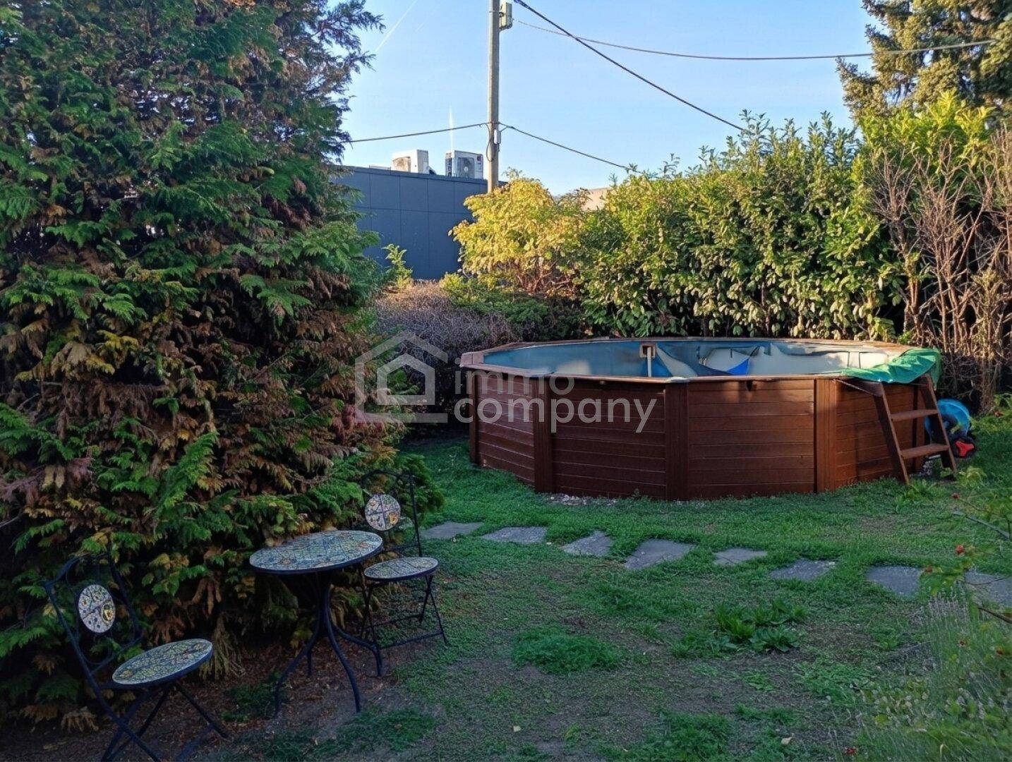 Gepflegter Gartenbereich mit Rasenfläche, kleinem Sitzplatz und einem runden Aufstellpool.