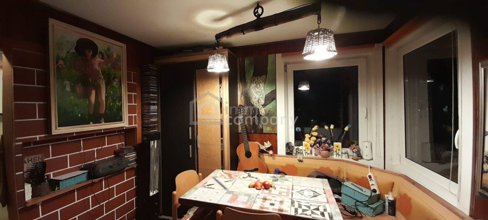 Rustikaler Essbereich mit Holzwänden, Fenstern und gemütlicher Beleuchtung, dekoriert mit Bildern.