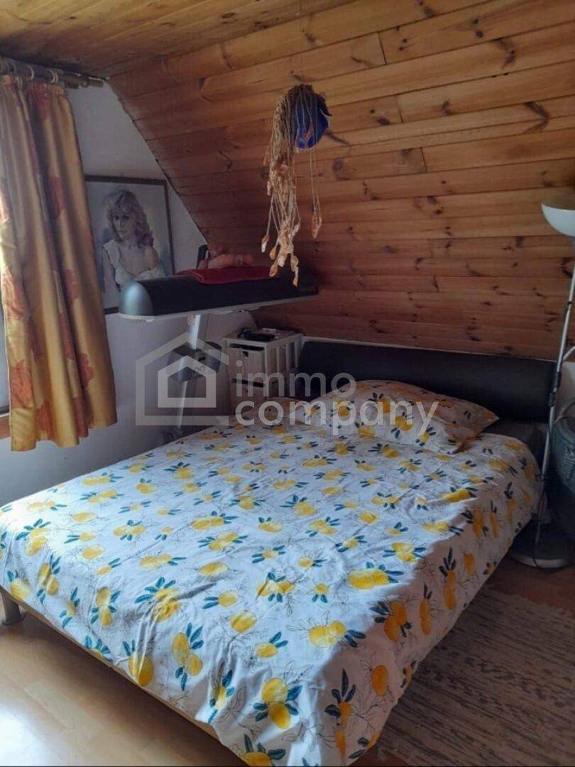 Gemütliches Schlafzimmer mit Holzwänden, Dachschräge und Doppelbett mit bunter Bettwäsche.