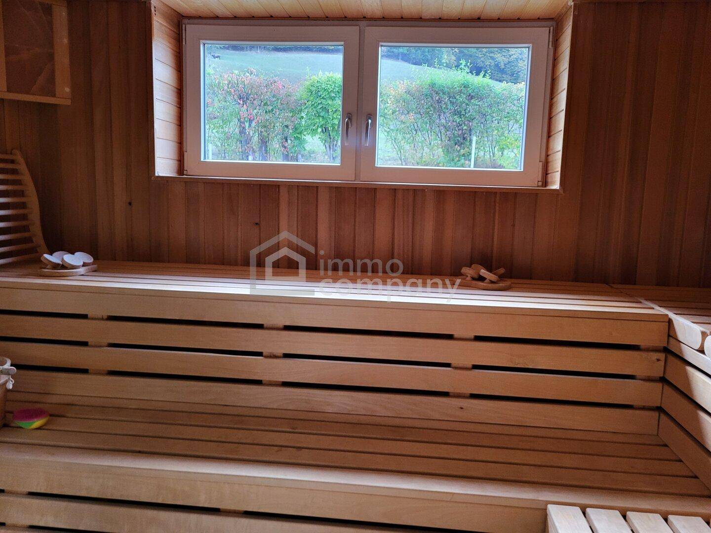 Gemütliche Holzsauna mit Fenster und traditionellen Bänken für Entspannung.