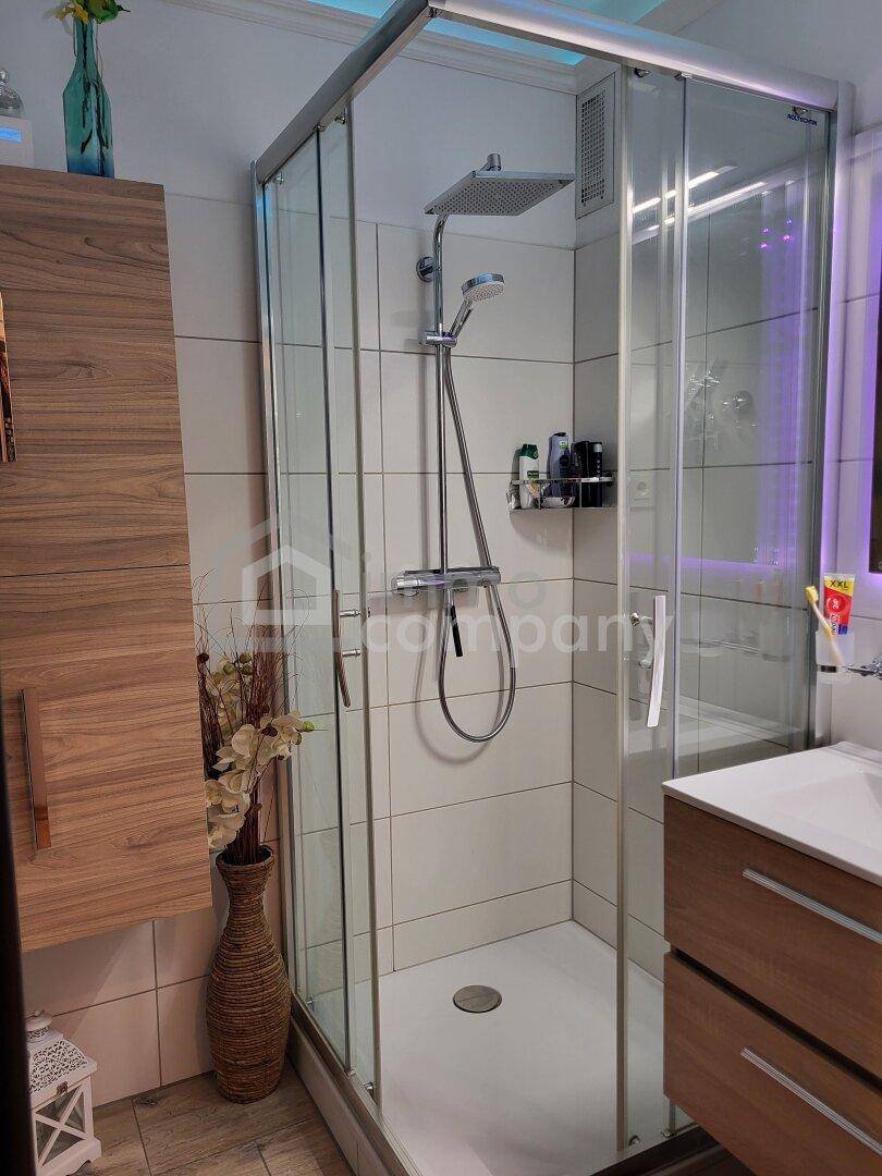 Modernes Badezimmer mit Duschkabine, Regendusche und Holzwaschtisch mit integriertem Waschbecken.