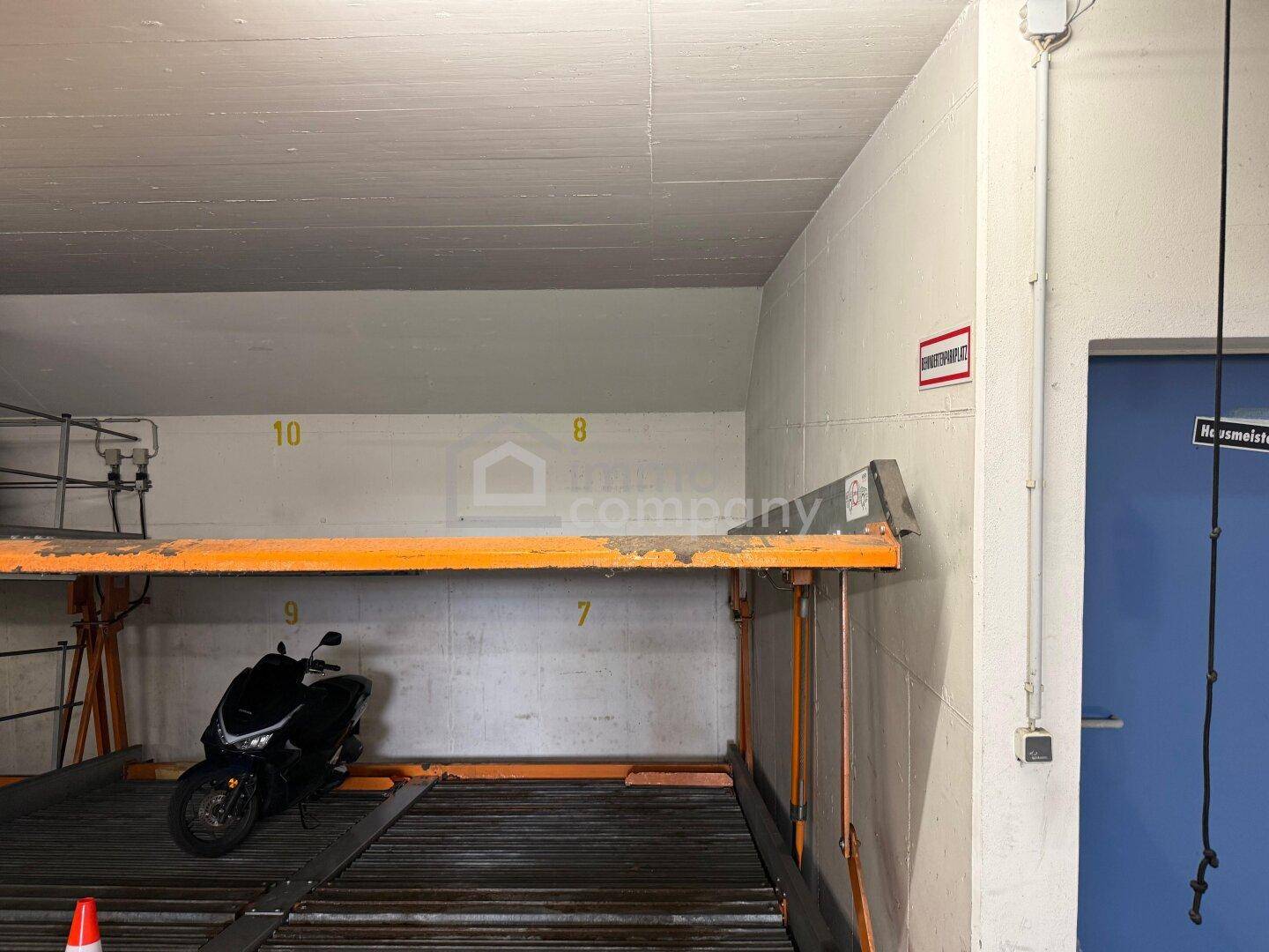 Tiefgarage mit Parkliftsystem und Stellplatz für Fahrzeuge, inklusive Motorrad.