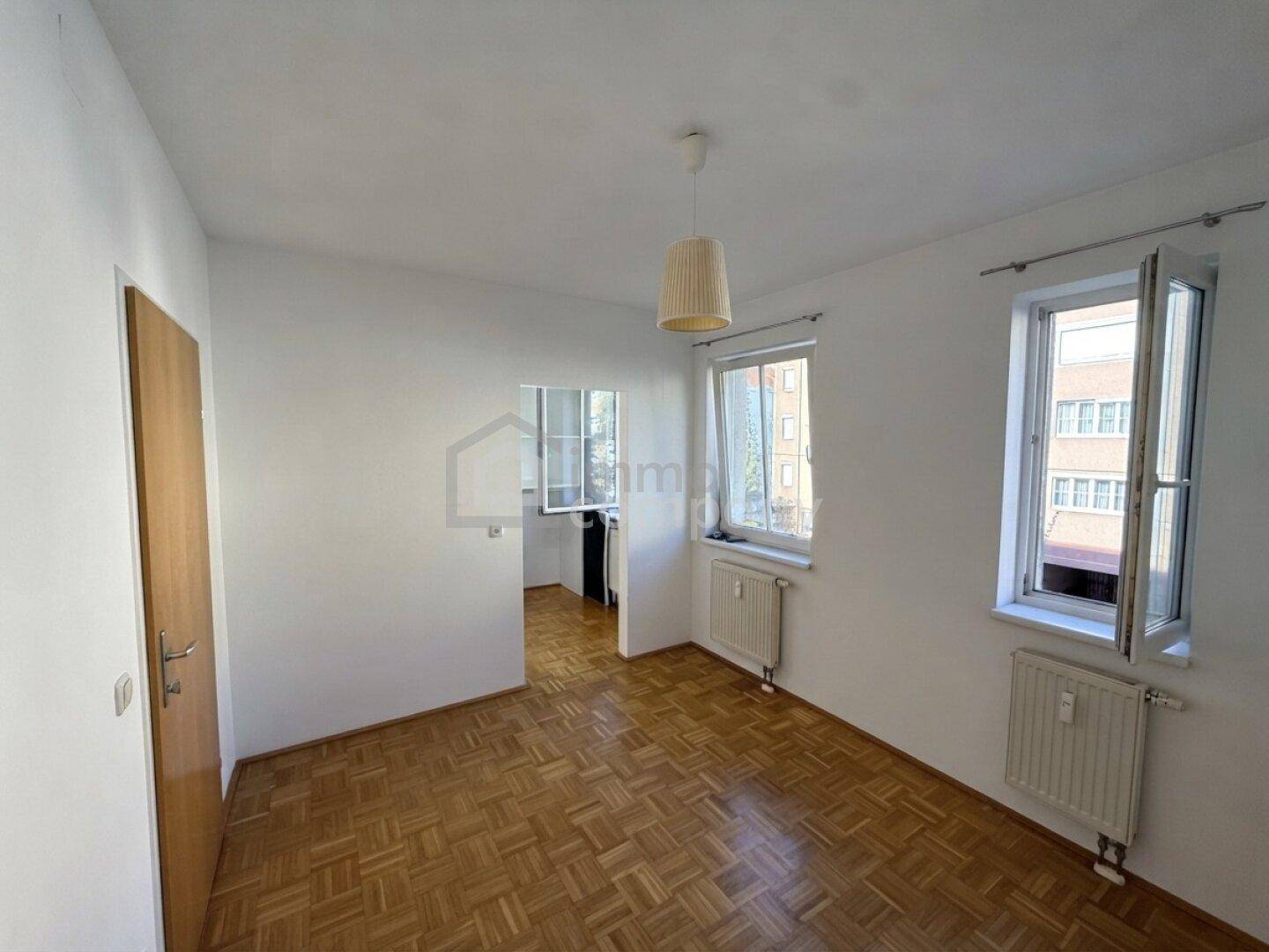 Helles Zimmer mit Parkettboden und zwei Fenstern, ideal als Schlaf- oder Arbeitszimmer.