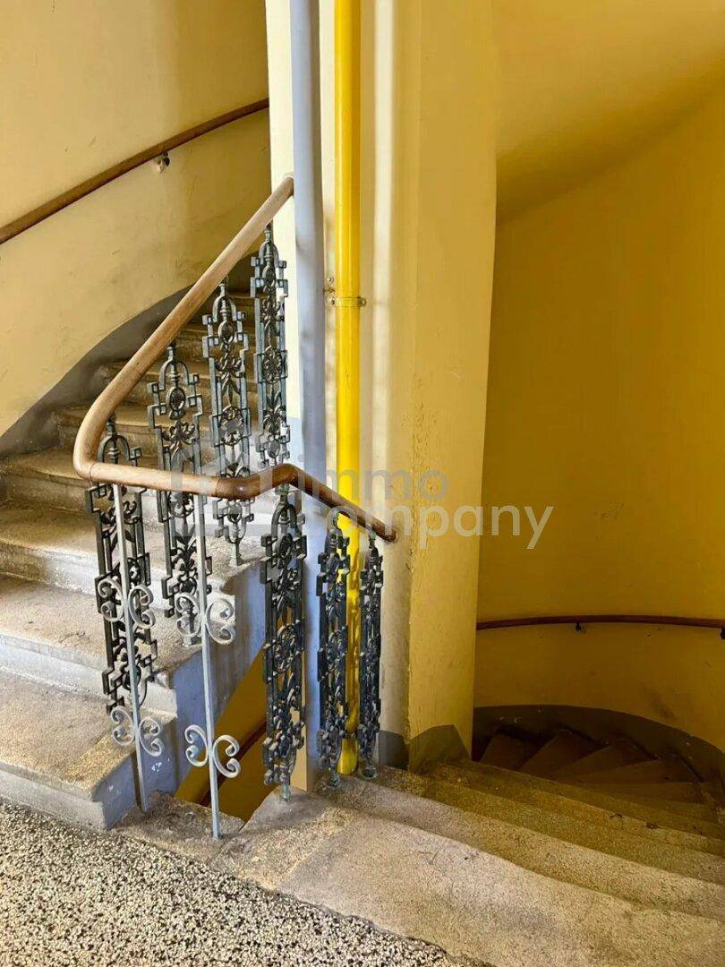 Historisches Treppenhaus mit schmiedeeisernem Geländer und gelben Akzenten in einem Altbau.