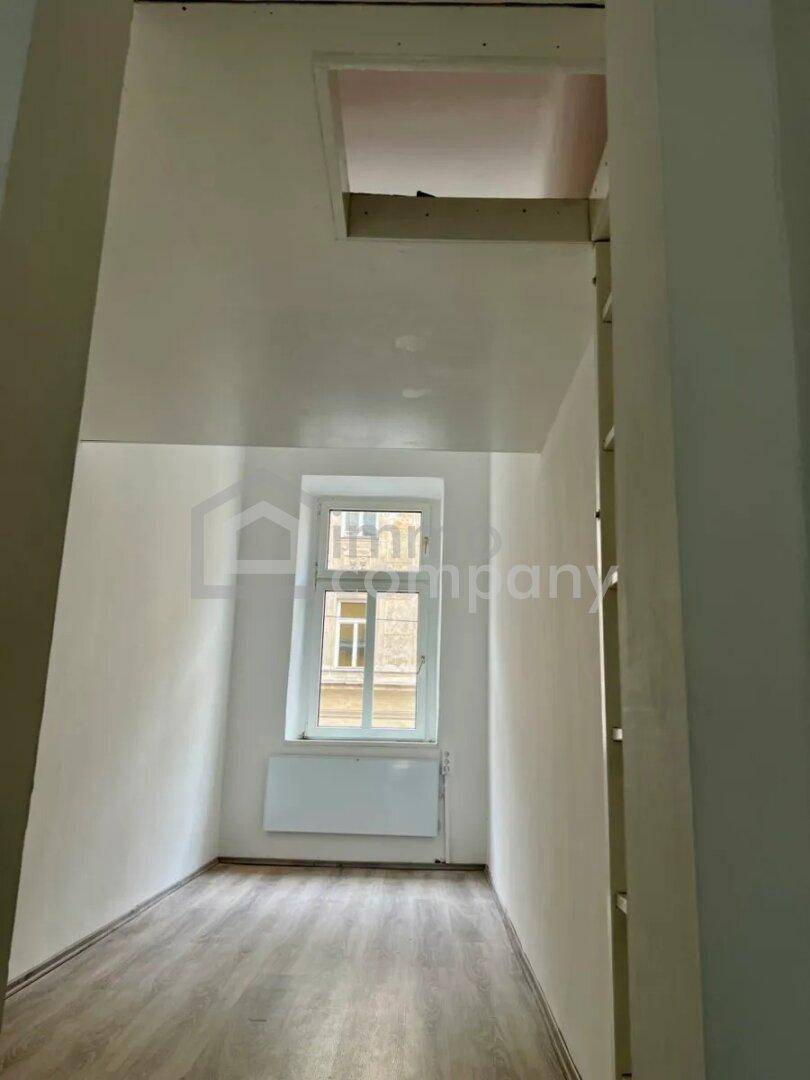 Leerer Raum mit Laminatboden und einem Fenster, das Licht hereinlässt.