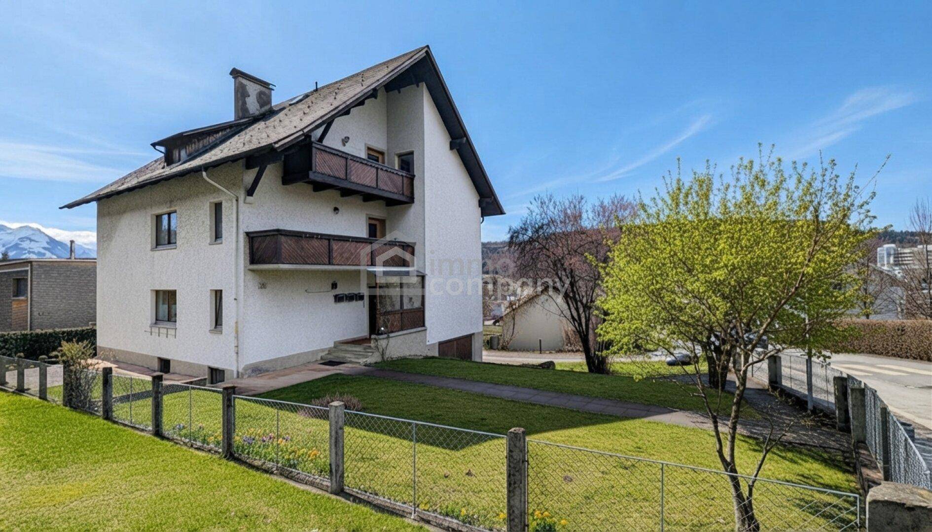 Freistehendes Haus mit Satteldach, Balkonen und gepflegtem Vorgarten mit Bergblick.