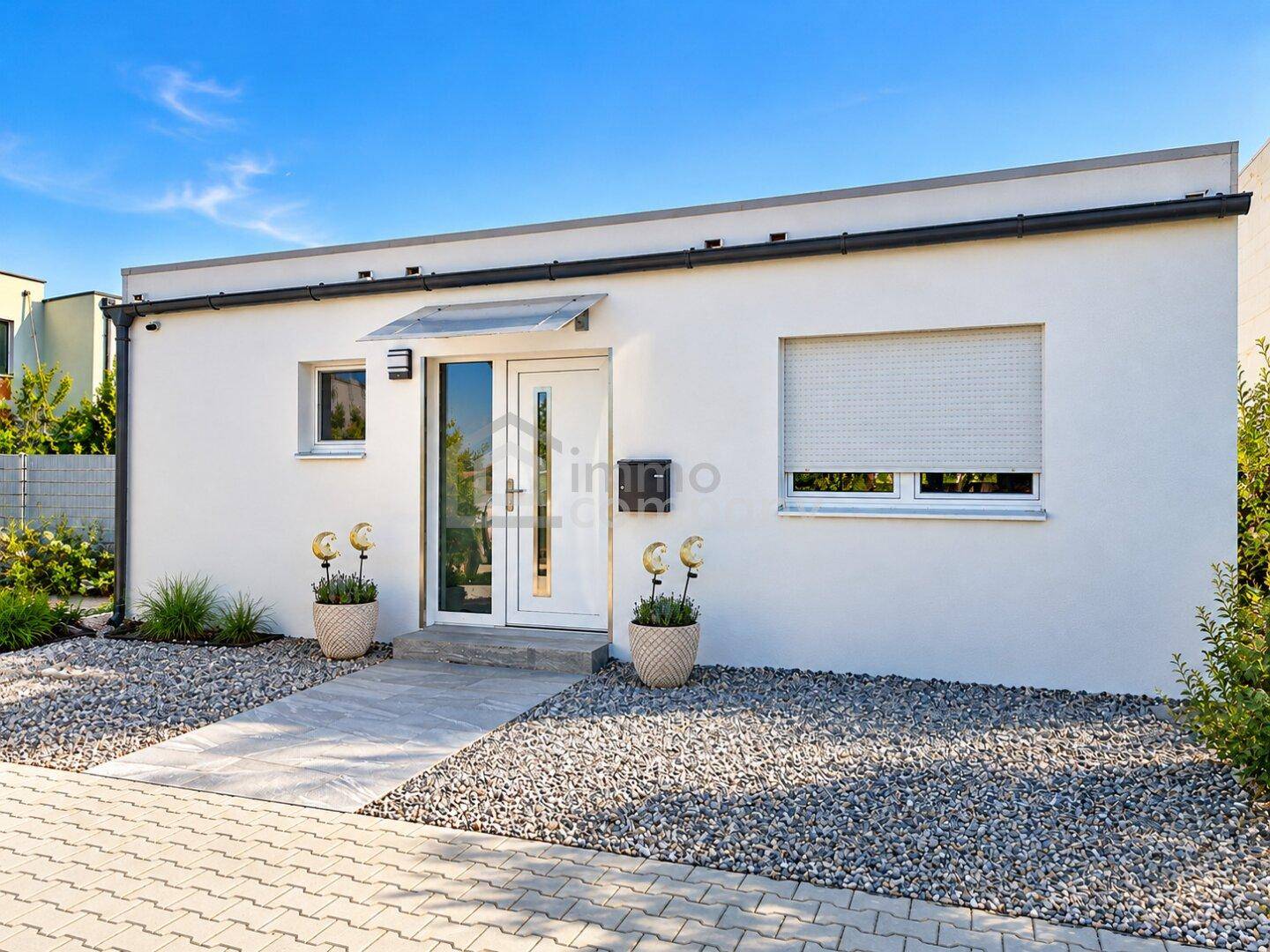Moderne Hausfassade mit weißem Putz, Flachdach und Eingangsbereich.