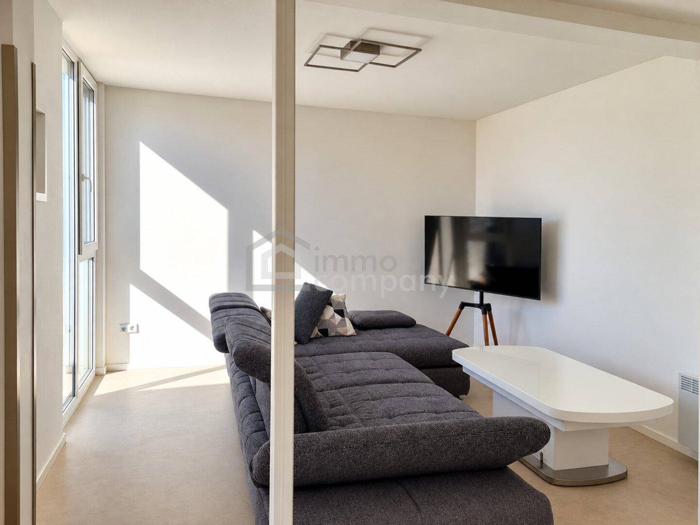 Gemütliches Wohnzimmer mit großem Ecksofa und modernem Fernseher.