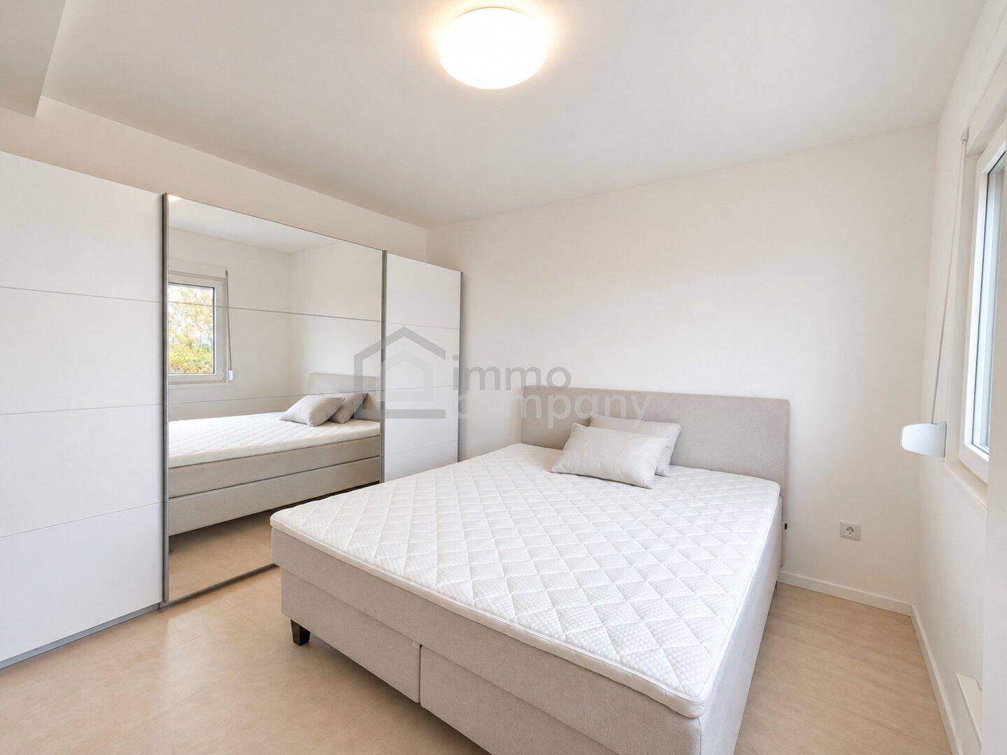 Helles Schlafzimmer mit Doppelbett und großem Spiegelschrank.