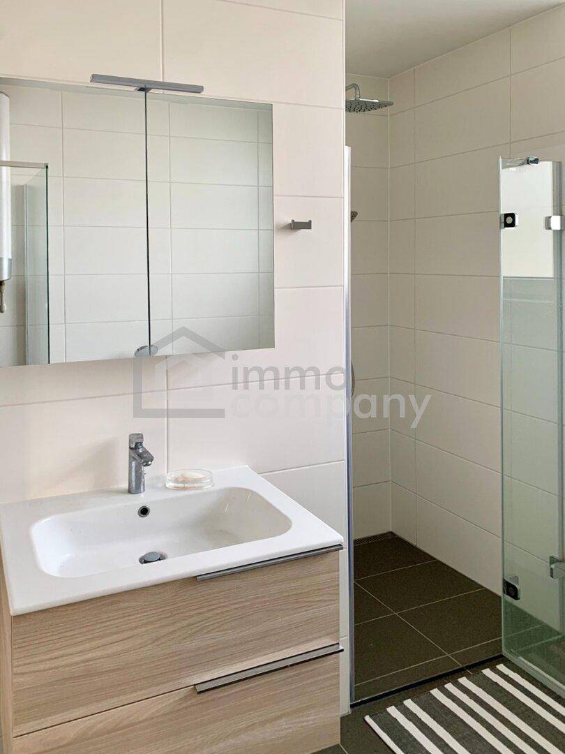 Modernes Badezimmer mit Waschtisch, Spiegelschrank und ebenerdiger Dusche.