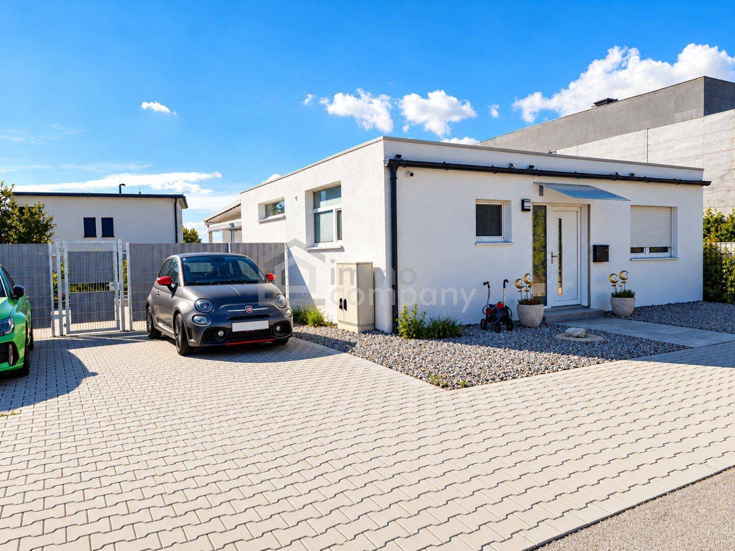 Moderne Hausfassade mit Einfahrt und Parkplatz für ein Fahrzeug.