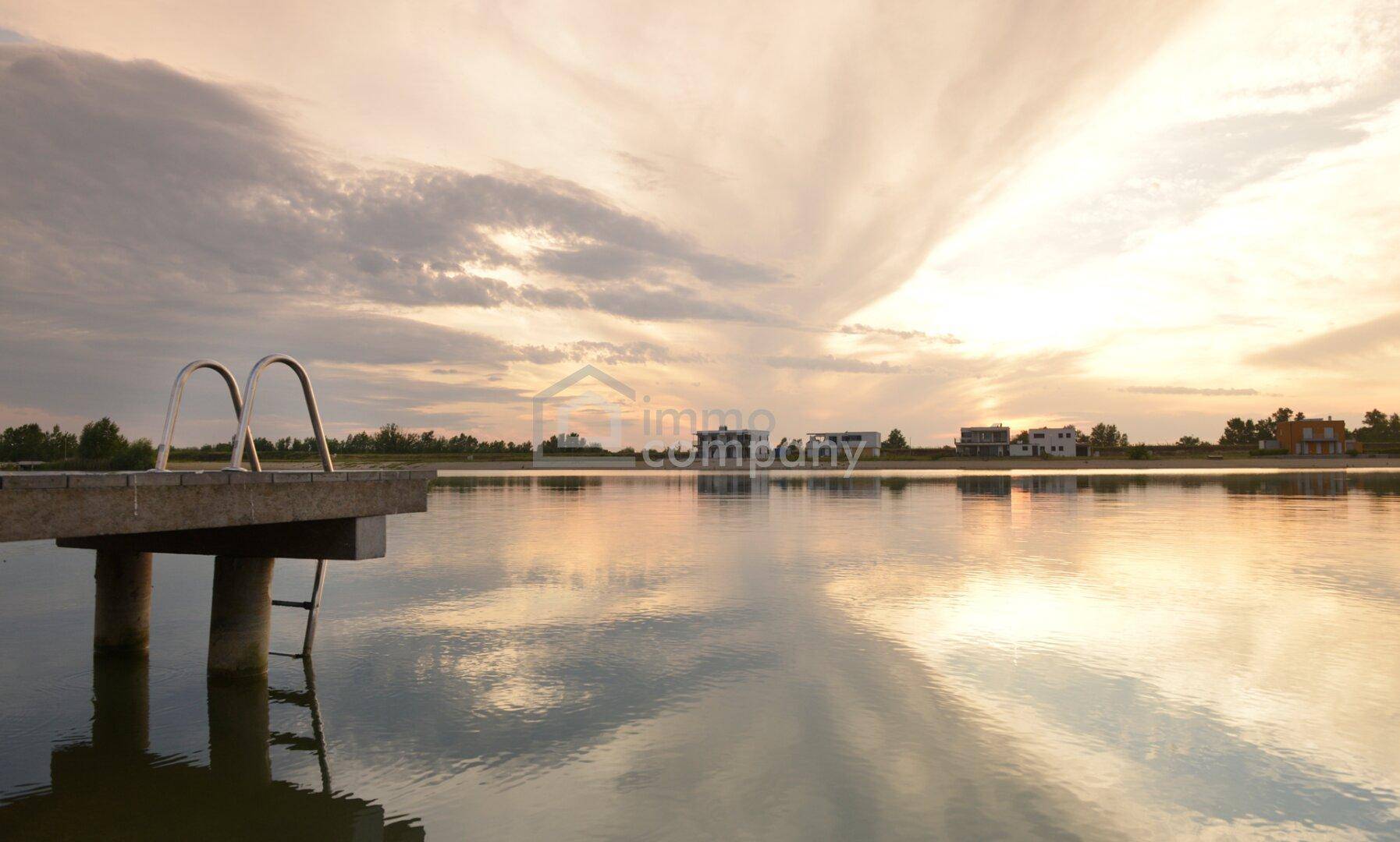 Malerischer Sonnenuntergang über dem See mit Steg und ruhiger Wasseroberfläche.