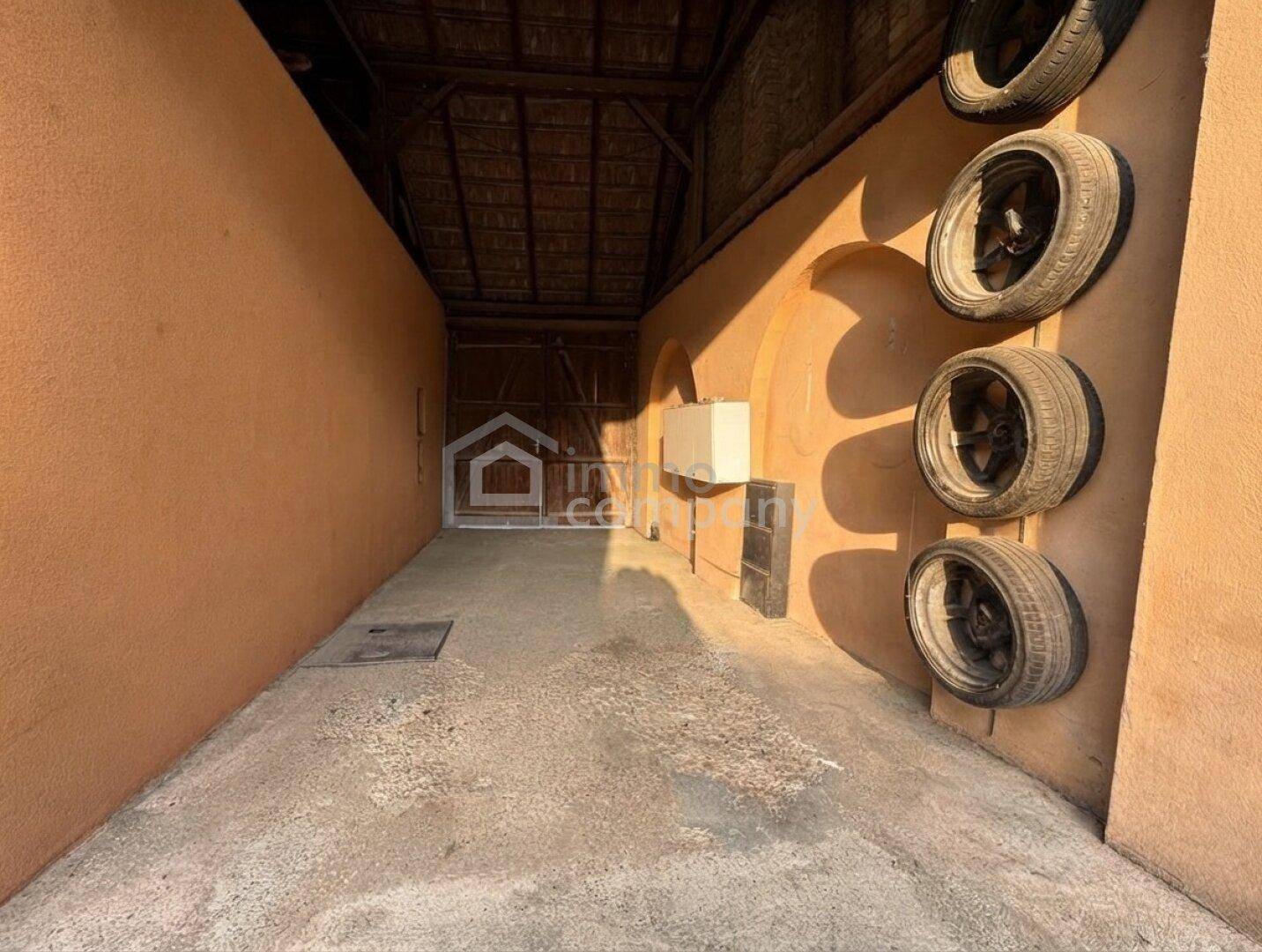 Geräumige Garage oder Abstellraum mit Betonboden und Reifen an der Wand.