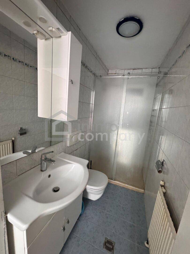Badezimmer mit Duschbereich, WC, Waschbecken und hellblauen Fliesen.