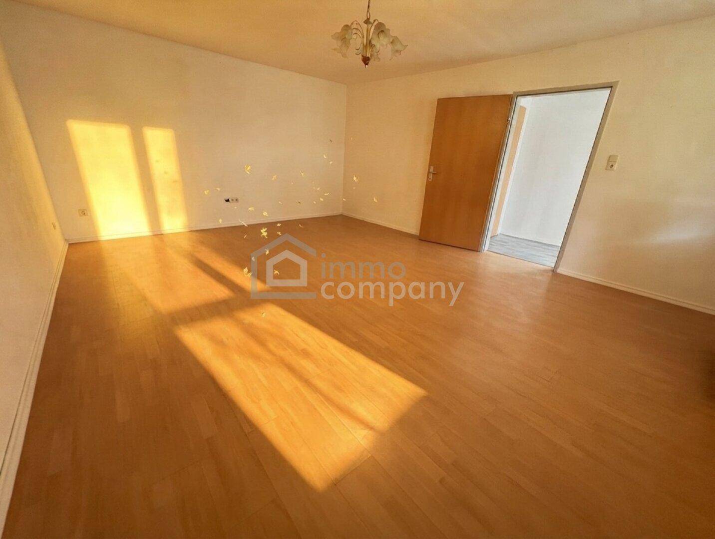 Helles Wohnzimmer mit Parkettboden und viel natürlichem Lichteinfall durch die Fenster.