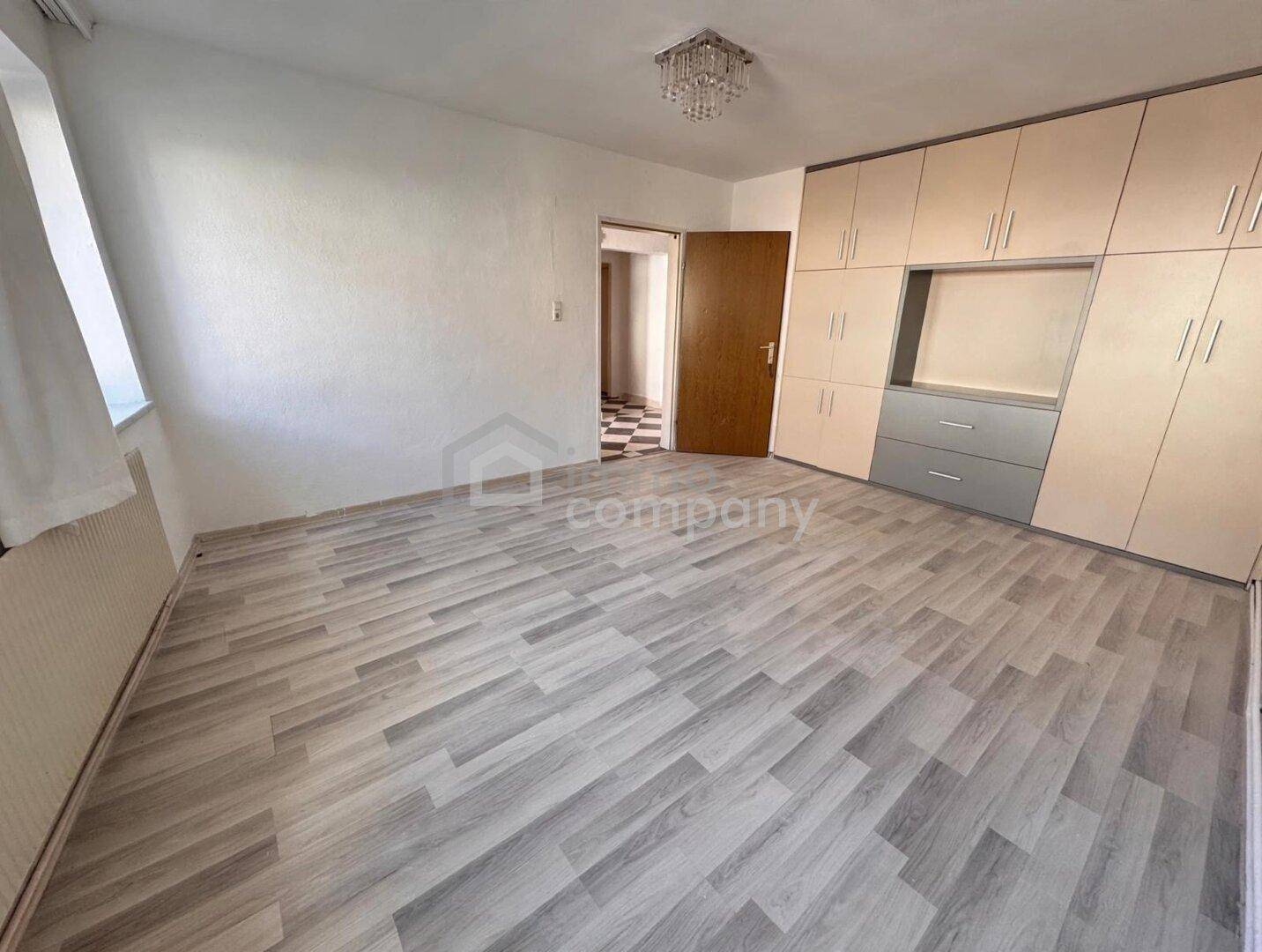 Schlafzimmer mit Holzoptikboden, Einbauschrank und Fenster für natürliches Licht.