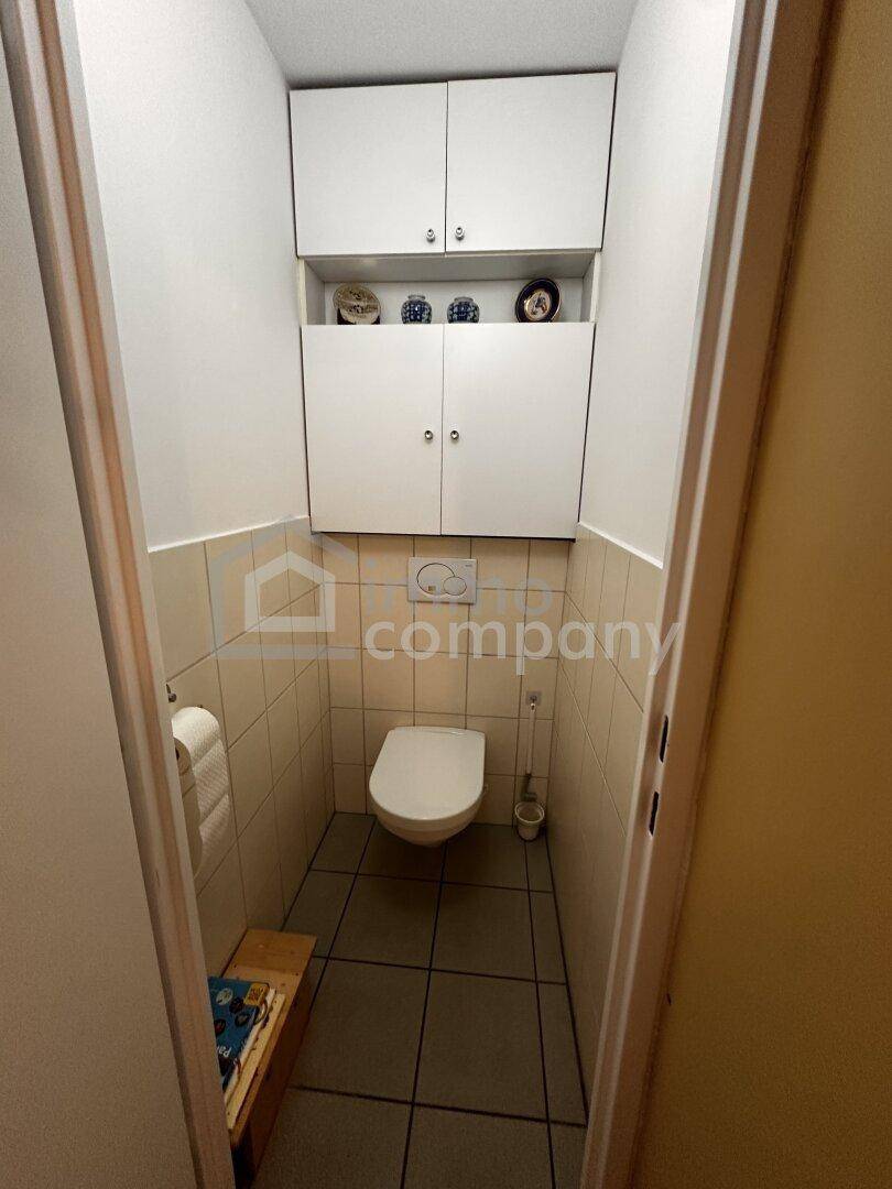 Kleines Gäste-WC mit Wand-WC, Fliesen und praktischen Wandschränken für zusätzlichen Stauraum.