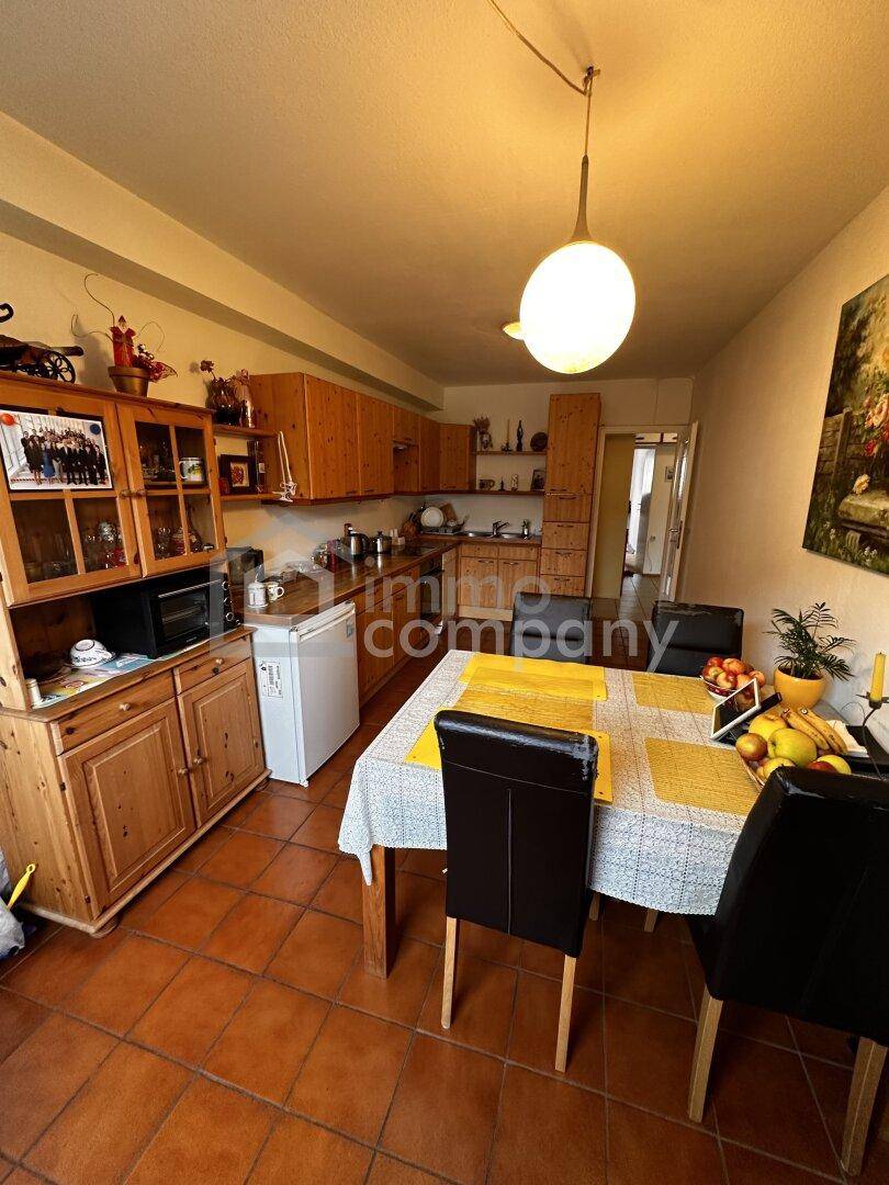 Wohnküche mit Holzschränken, Esstisch und Terrakottafliesen, bietet Platz zum gemeinsamen Essen.