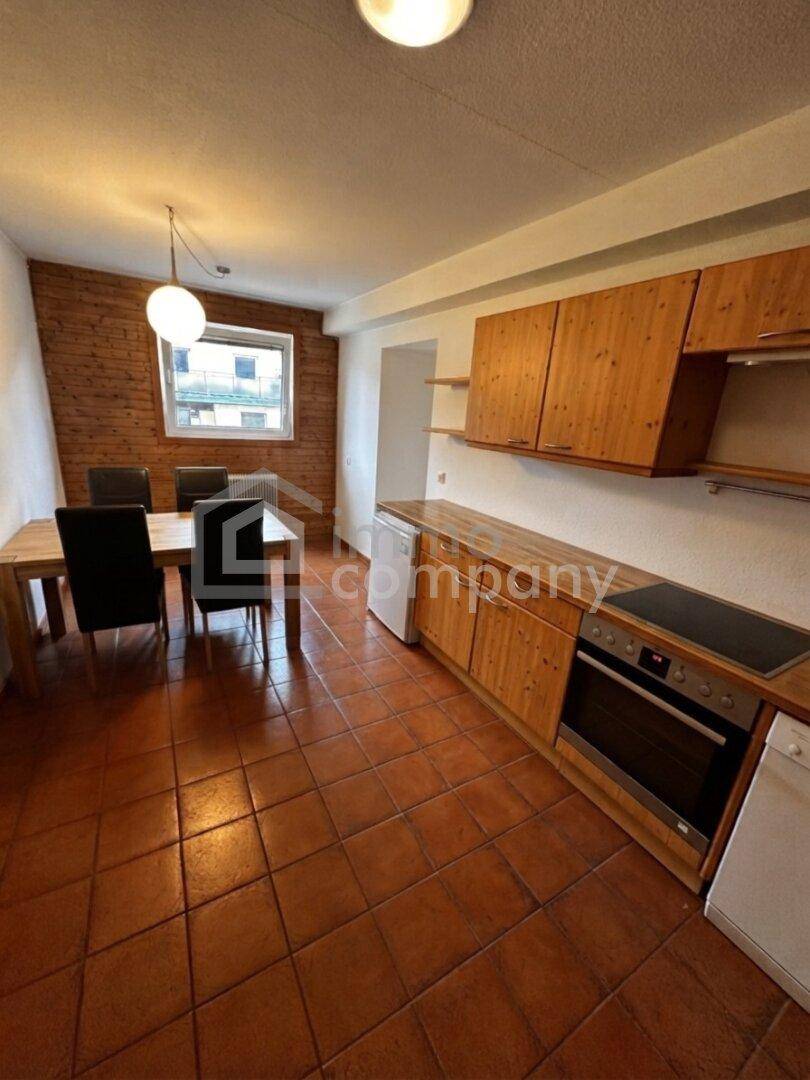 Funktionale Küche mit Holzfronten, integriertem Backofen und Essbereich, ideal für Familienmahlzeiten.