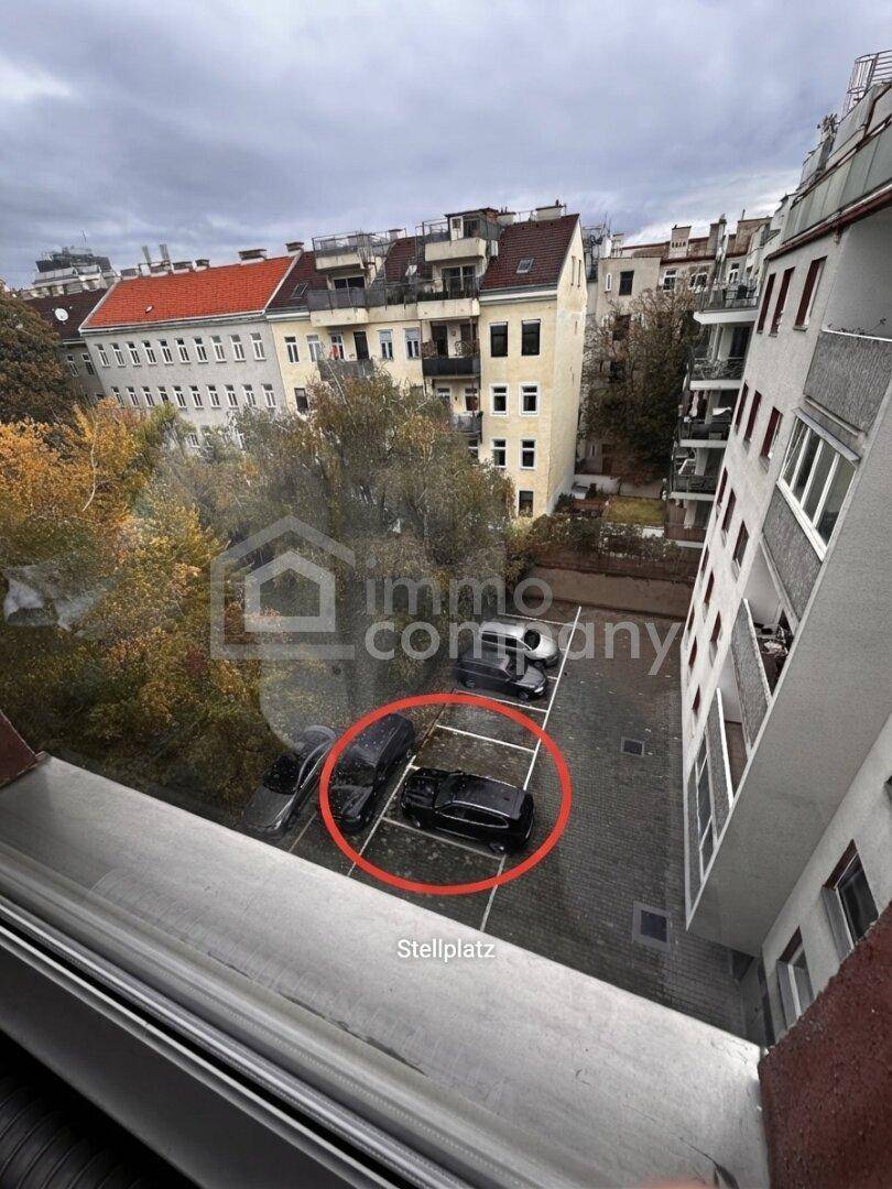 Außenansicht eines Parkplatzes mit mehreren Fahrzeugen, umgeben von städtischen Gebäuden.