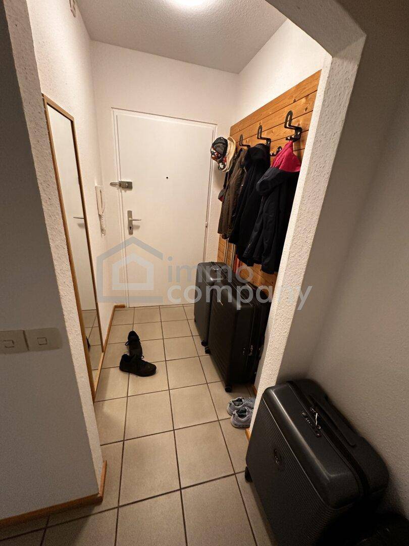 Eingangsbereich mit Fliesenboden, Garderobe und Spiegel, bietet Platz für Mäntel und Schuhe.