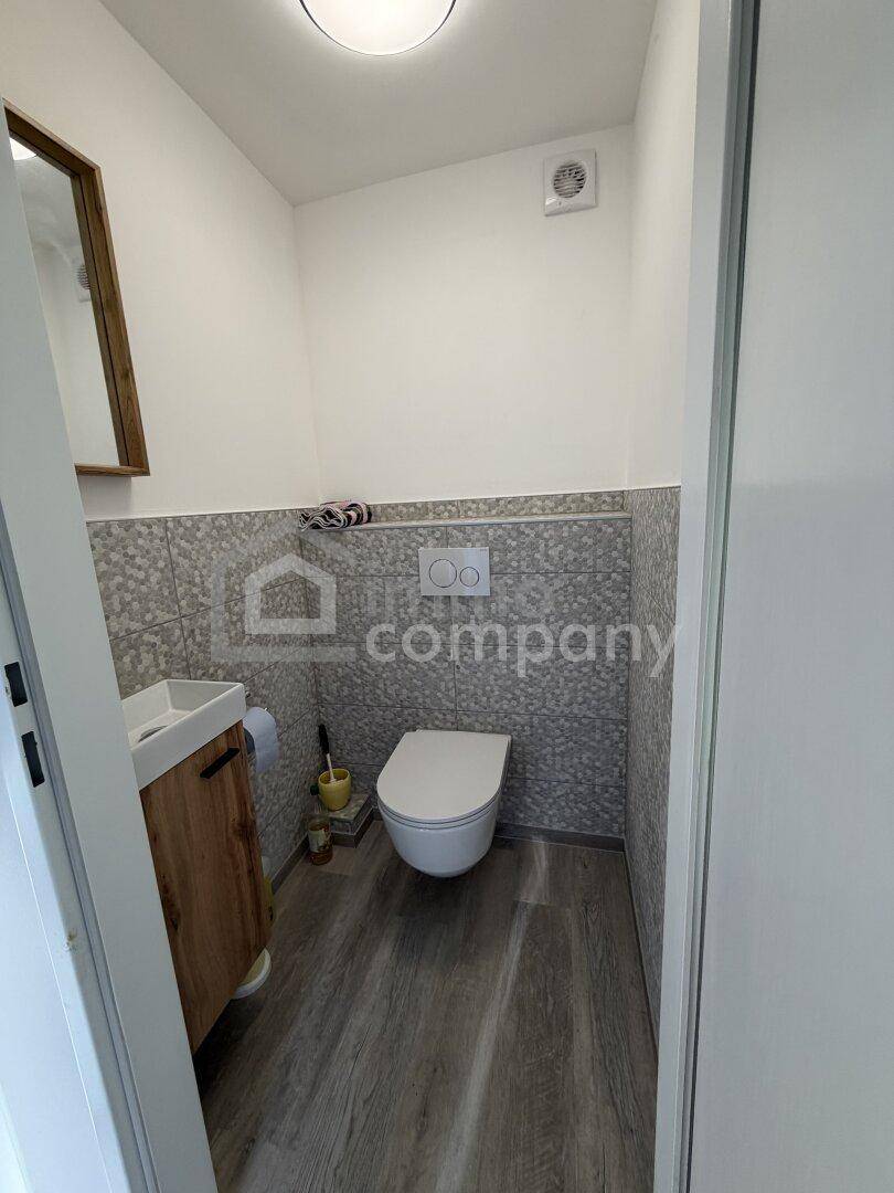 Modernes Gäste-WC mit Wand-WC, kleinem Waschbecken und grauen Fliesen.