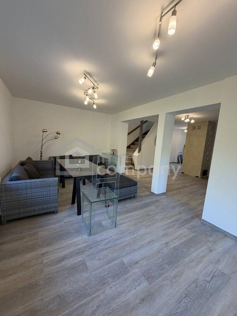 Geräumiges Wohnzimmer mit Laminatboden, Treppenaufgang und Blick auf den Essbereich.