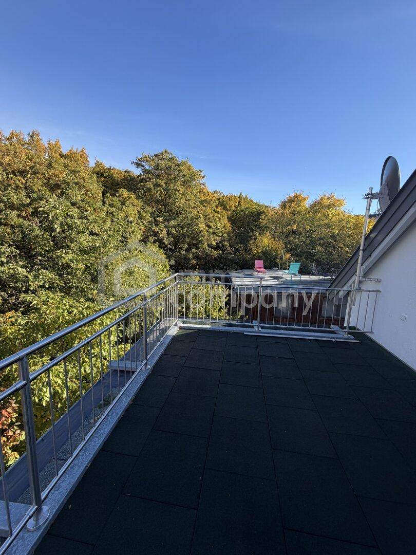 Sonniger Balkon mit Metallgeländer und Panoramablick auf die grüne Umgebung und den Himmel.