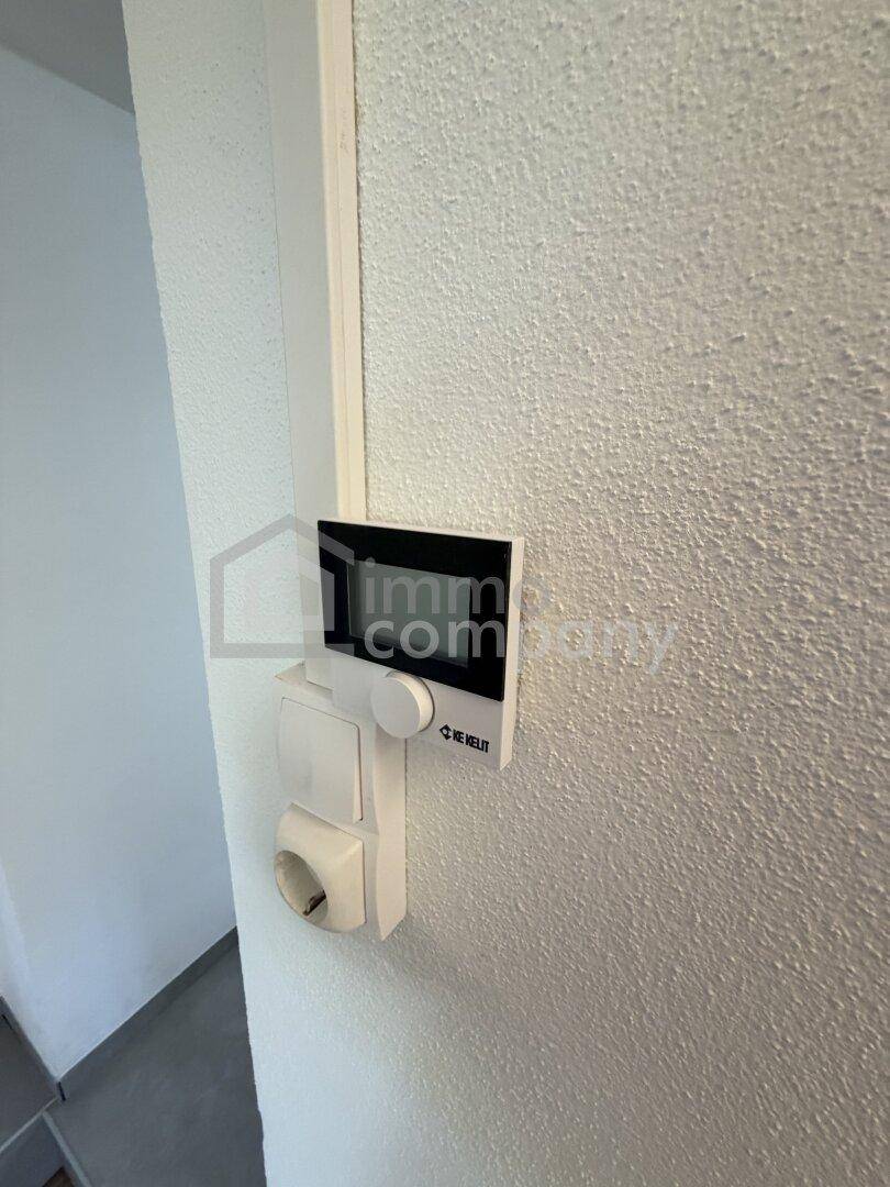 Nahaufnahme einer Steckdose und eines Lichtschalters an einer strukturierten Wand.