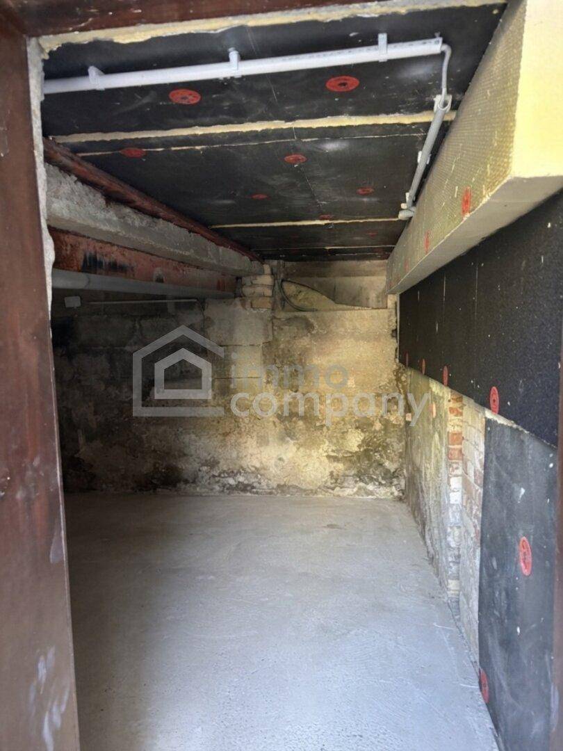 Unfertiger Kellerraum mit Betonboden und sichtbaren Leitungen und Isolierung.