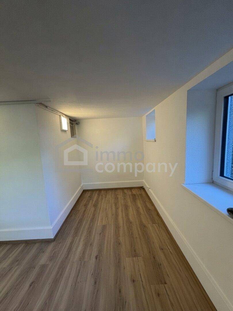 Heller Kellerraum mit neuem Laminatboden und zwei Fenstern.