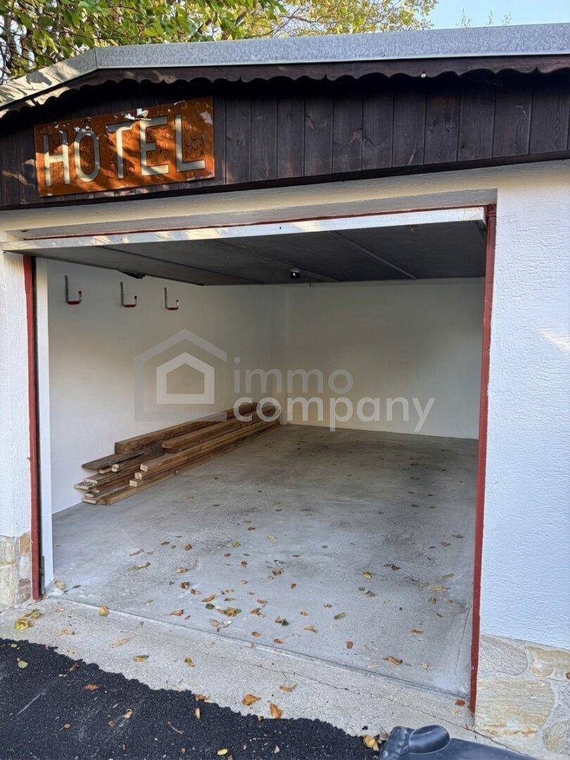 Leere Garage mit Betonboden und Holzbalken, bereit zur Nutzung oder Lagerung.