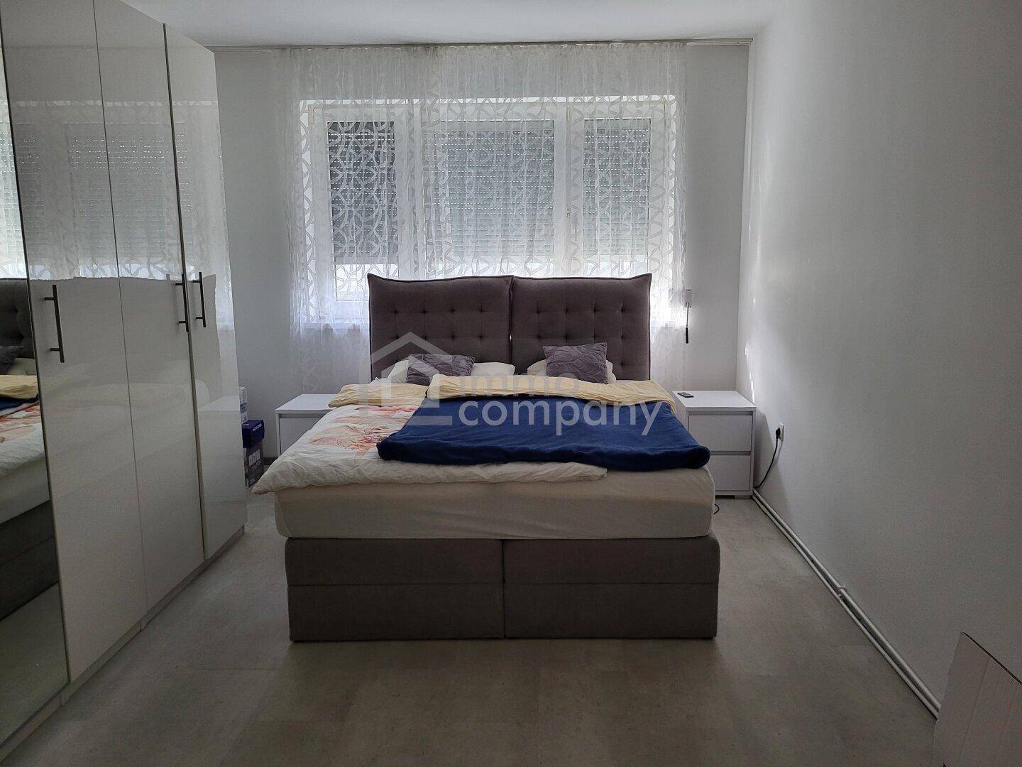 Geräumiges Schlafzimmer mit Doppelbett, Nachttischen und großen Fenstern für viel Tageslicht.