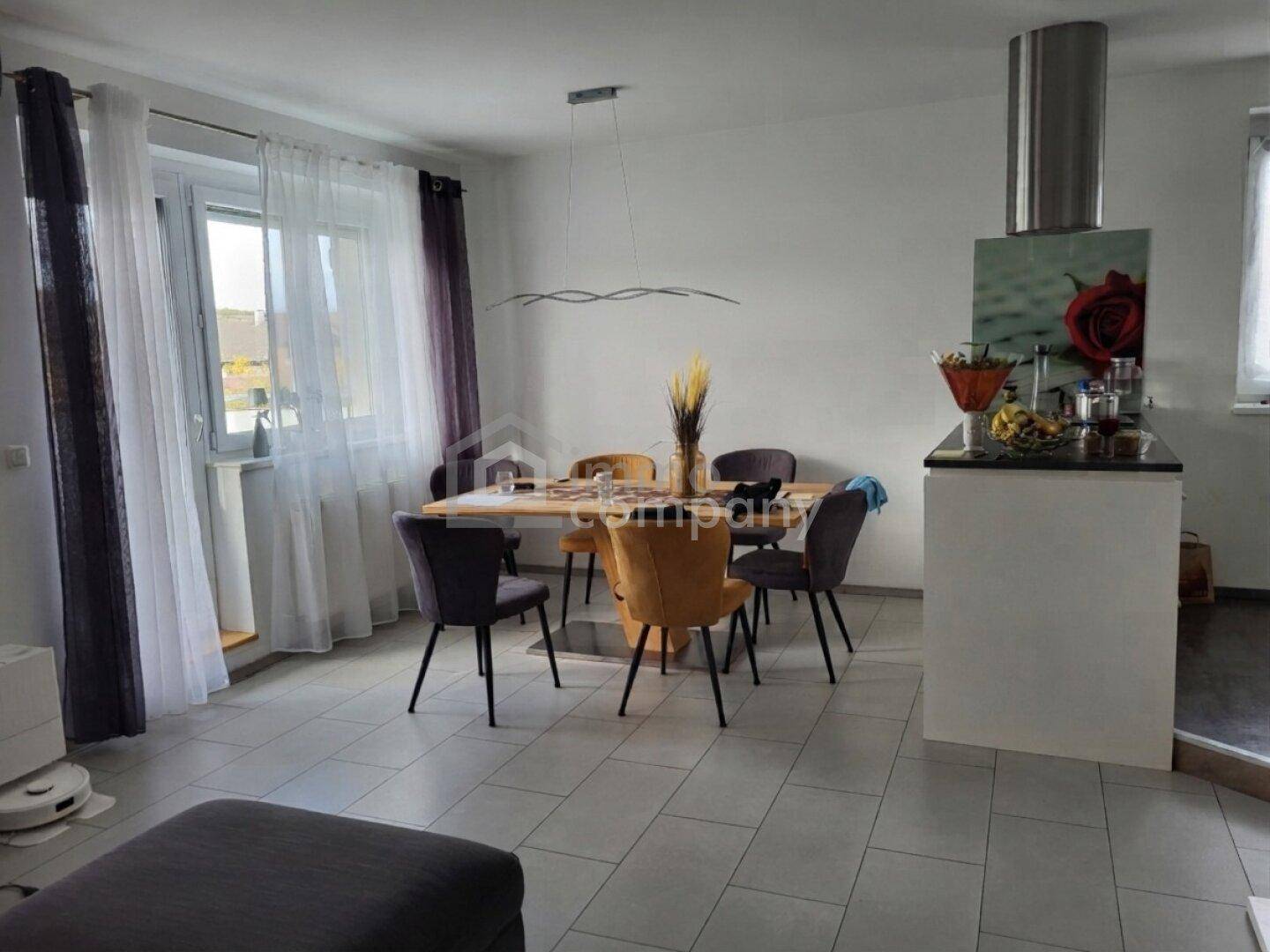 Heller Essbereich mit modernem Holztisch und Stühlen, offen zum Wohnbereich und zur Küche.