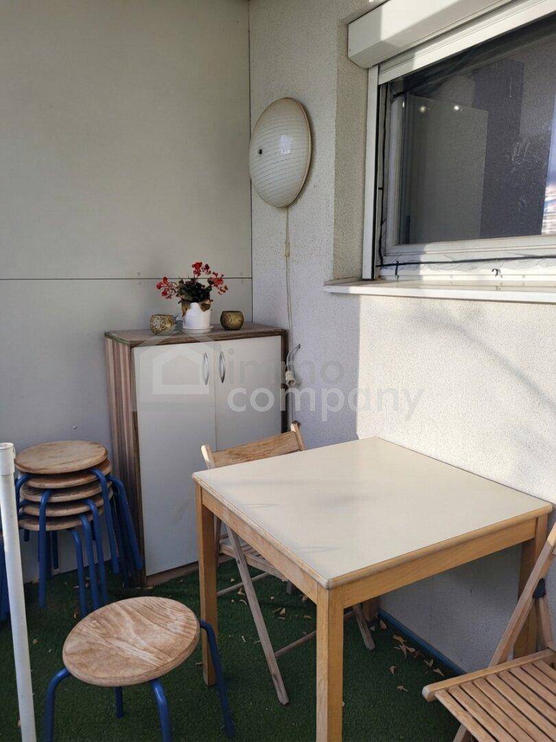 Kleiner Balkon mit Tisch und Hockern, ideal für eine Kaffeepause im Freien.