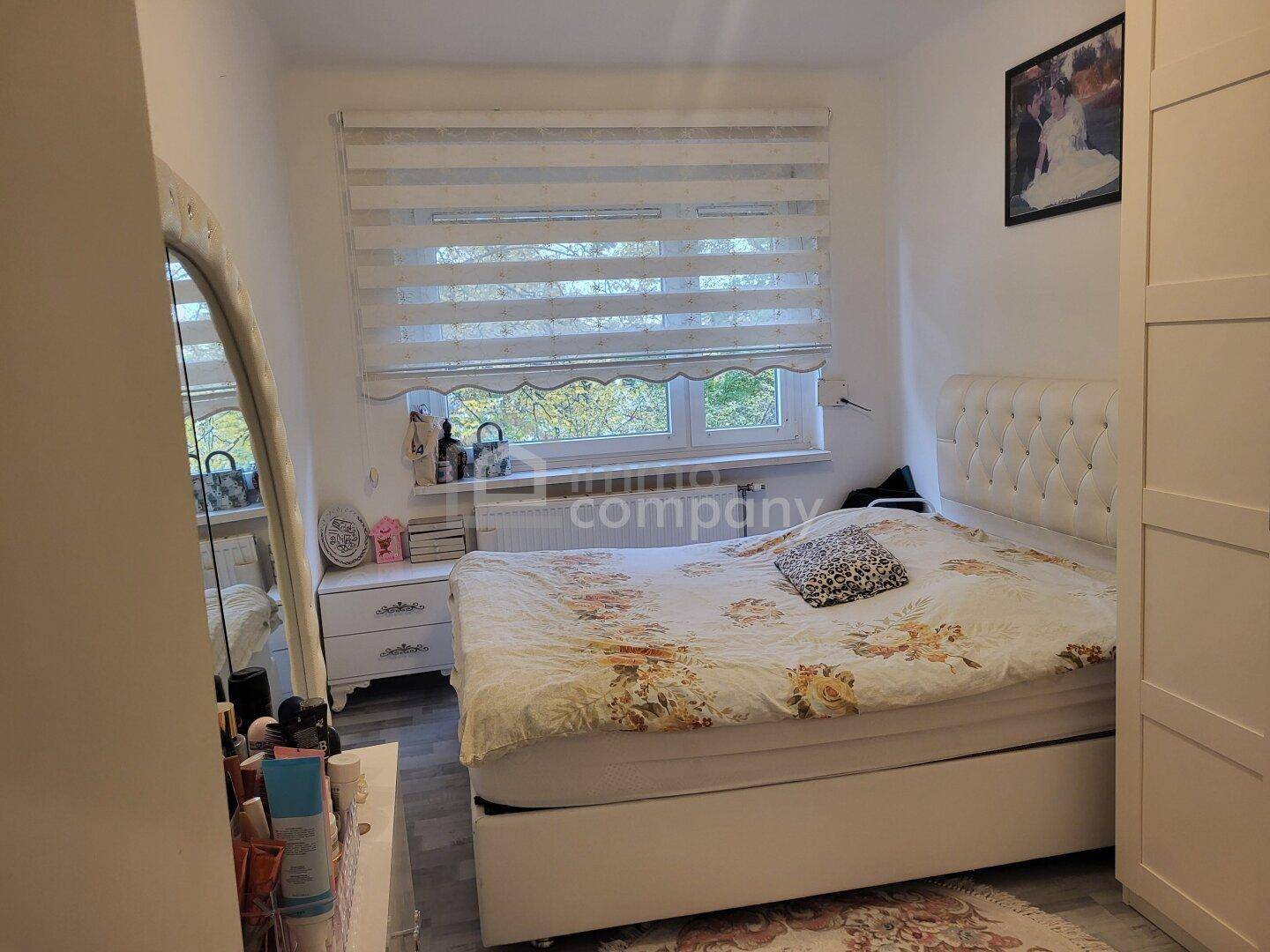 Helles Schlafzimmer mit großem Doppelbett, Nachttischen und einem Fenster mit Blick ins Grüne.