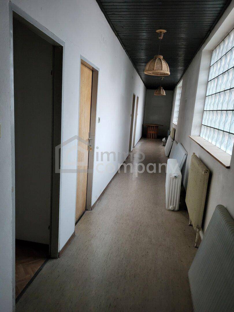 Heller Flur mit Korkboden, Holzdecken und Glasbausteinfenstern, Heizkörper an der Wand.