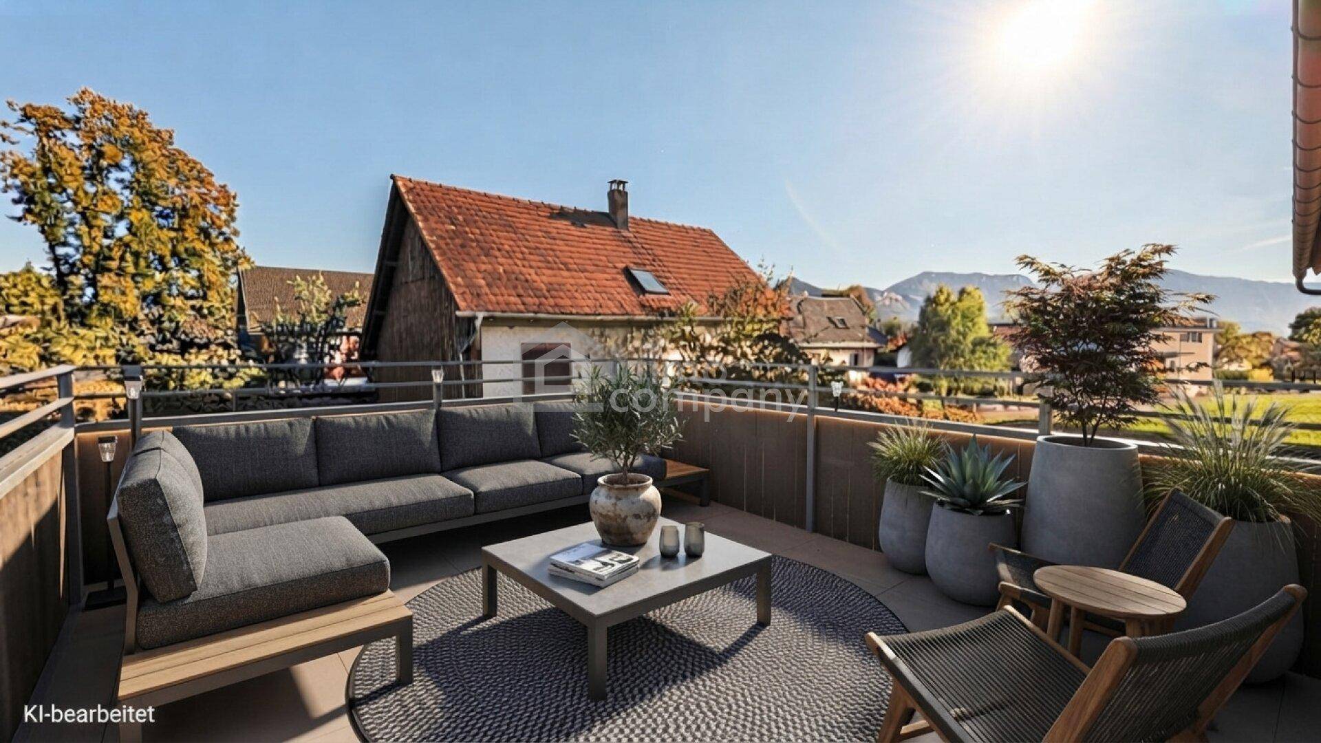 Möblierte Dachterrasse mit gemütlicher Sitzecke und Blick auf die umliegende Landschaft und Berge.