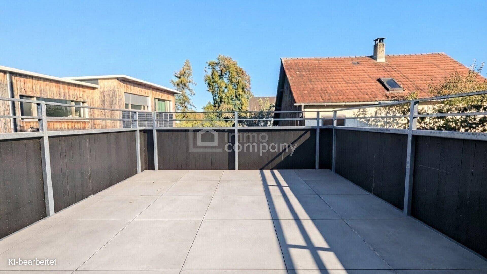 Geräumige, unmöblierte Dachterrasse mit Fliesenboden und umlaufendem Geländer, sonnig und offen.