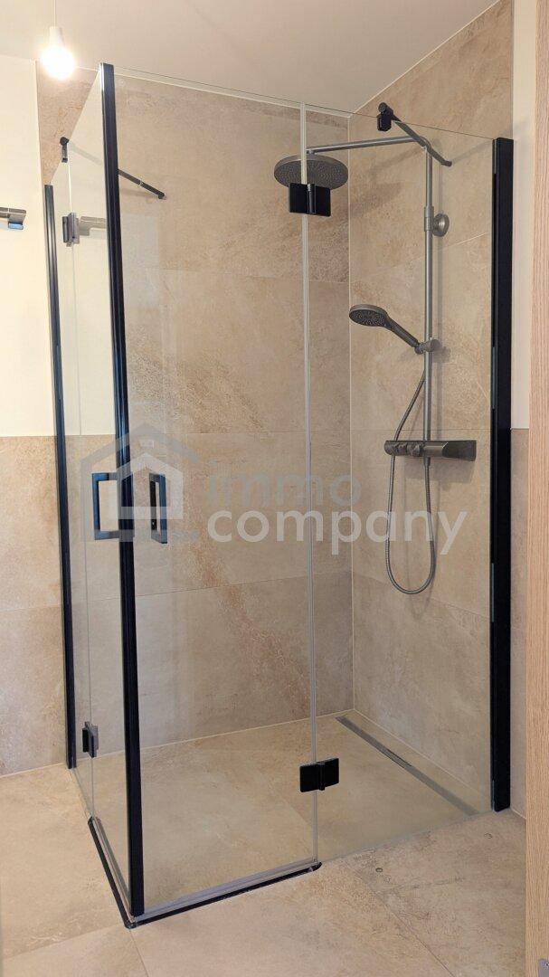 Geräumige Duschkabine mit Glaswänden und Regenduschkopf in einem modernen Badezimmer.