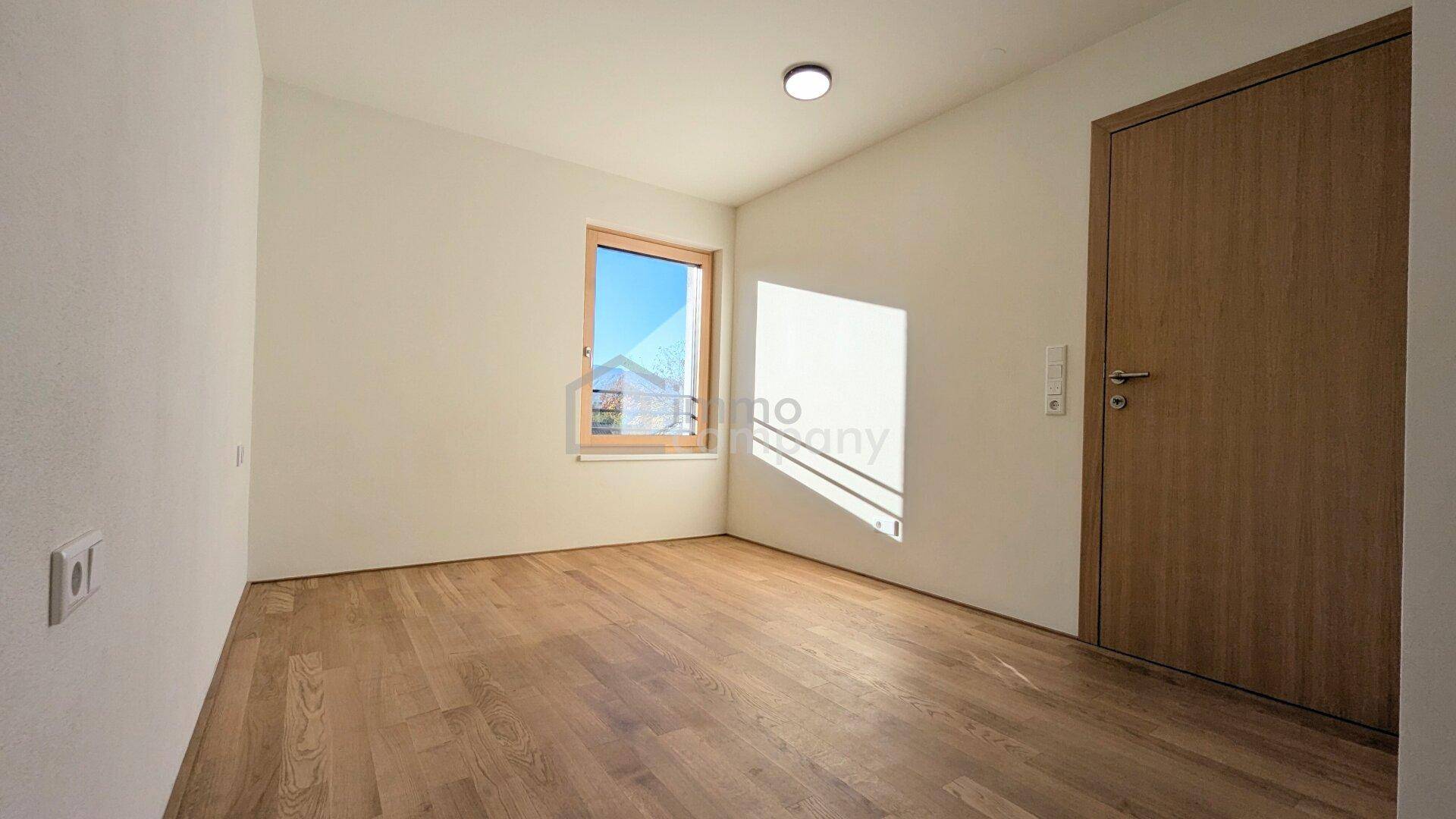 Geräumiges Schlafzimmer mit Holzboden und einer Holztür, hell und einladend gestaltet.