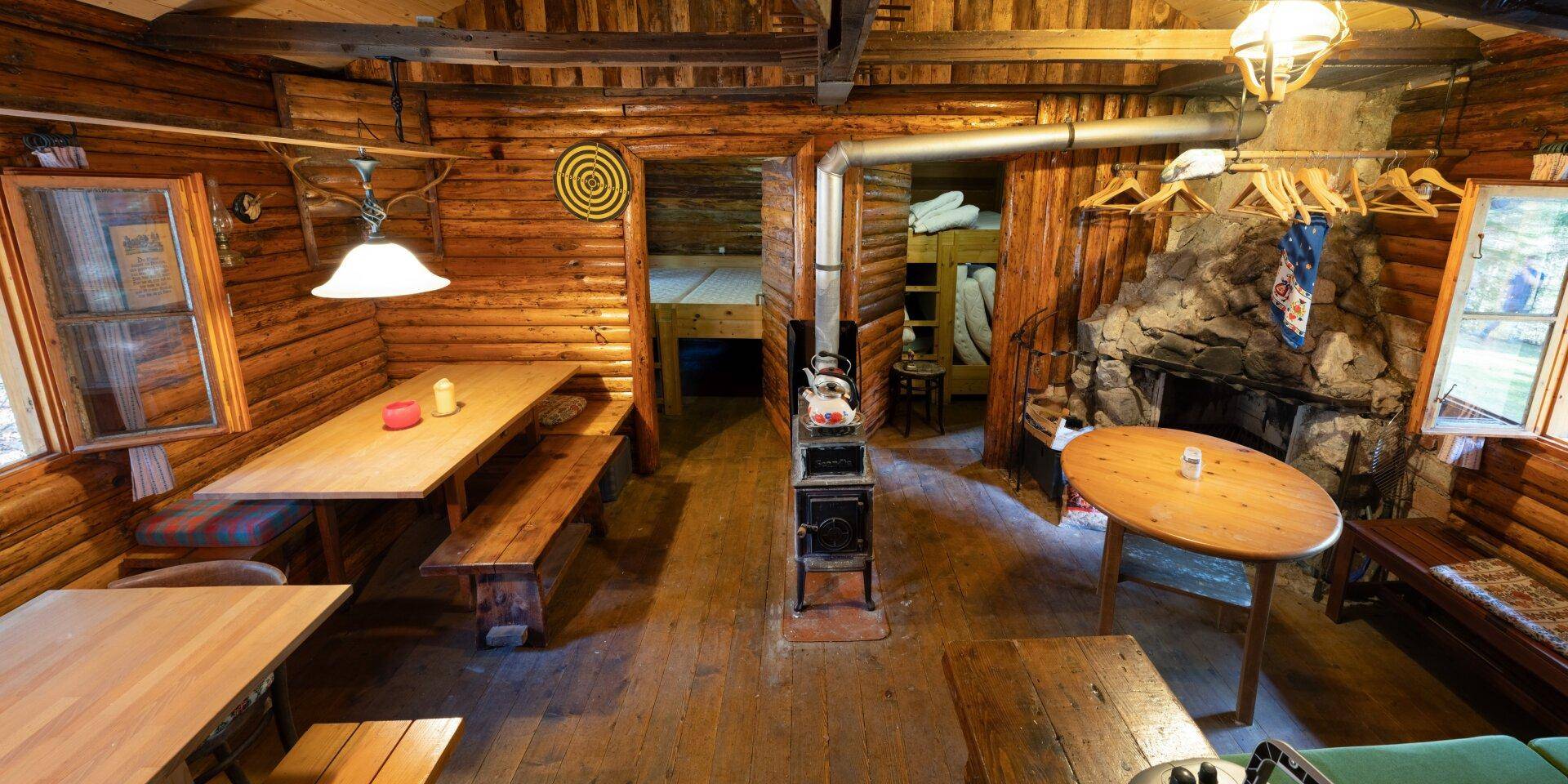 Geräumiger Wohn- und Essbereich mit Holzbalken, Kamin und mehreren Sitzgelegenheiten.
