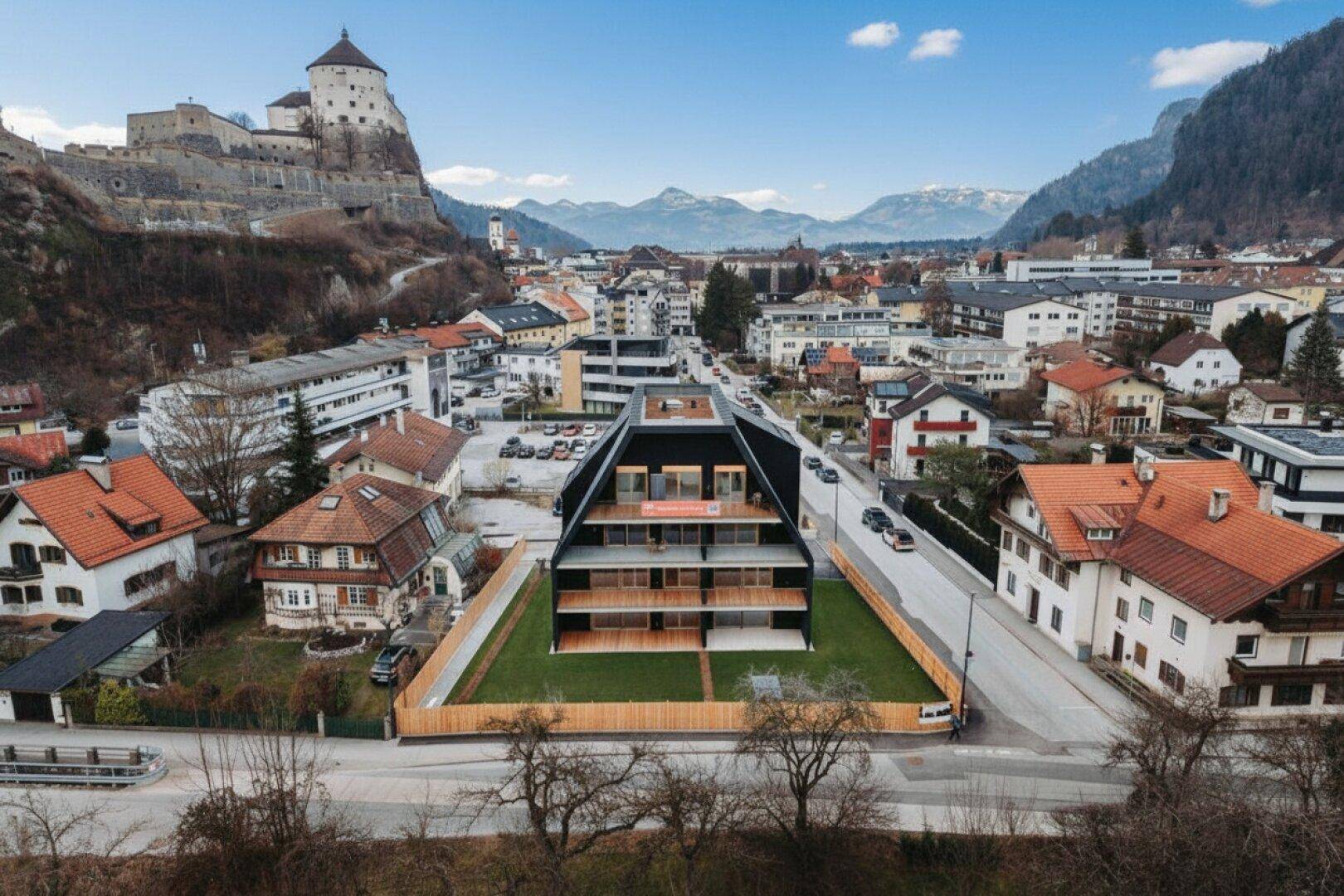 Panoramablick auf das moderne Wohngebäude mit einzigartiger Dachform und historischer Burgkulisse.